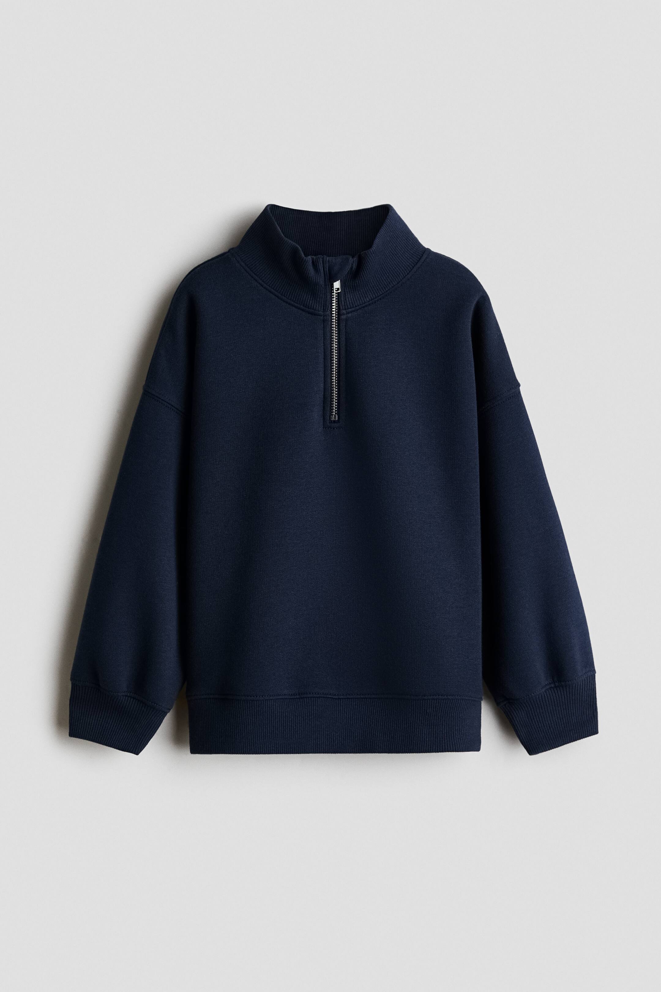 Xem ảnh lớn hơn: Một chiếc áo sweatshirt màu xanh navy có cổ đứng với khóa kéo 1/4 tông bạc ở phía trước. Thiết kế tay dài, bo tay áo và gấu áo bo rib.