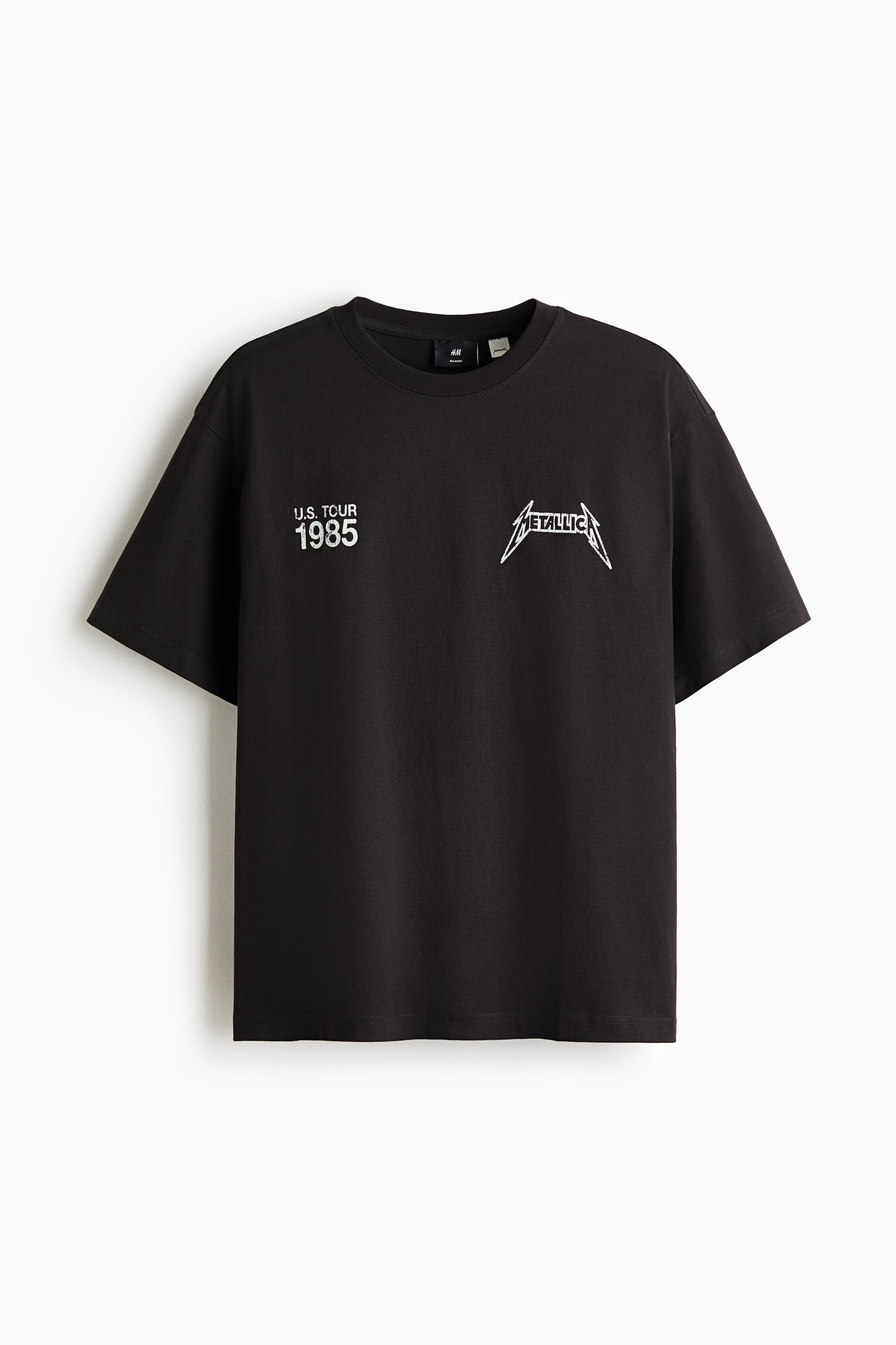 View larger image: A black T-shirt shows the front, featuring a round neckline with a narrow trim and dropped shoulders. White 'U.S. TOUR 1985' text and a 'Metallica' logo are printed on the chest.