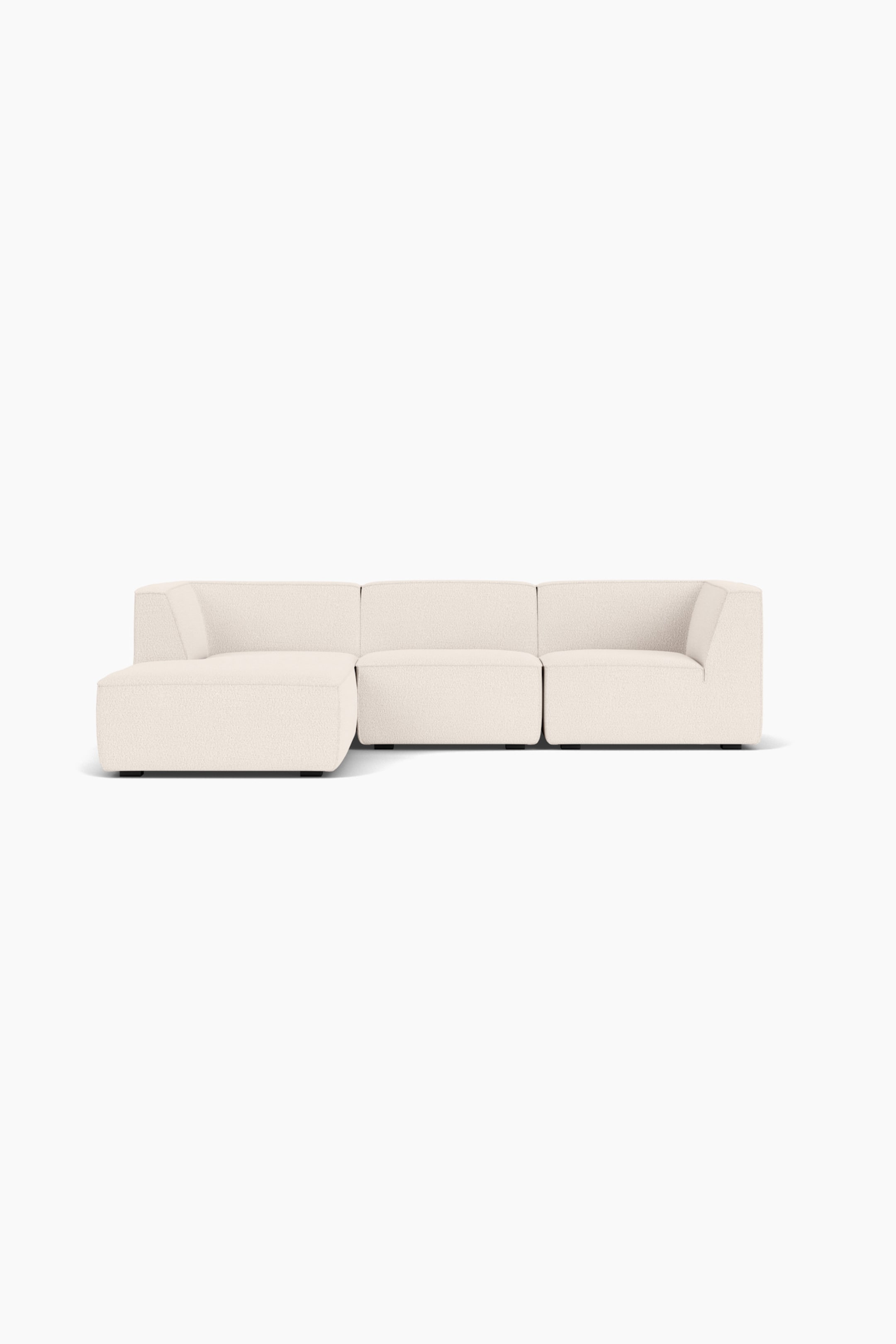 Größeres Bild ansehen: Ein modulares Ecksofa aus cremefarbenem, strukturiertem Stoff ist frontal ausgerichtet und verfügt über eine links angeordnete Chaiselongue, ein mittig platziertes Sitzmodul ohne Armlehnen sowie ein rechts angeordnetes Eckelement mit integrierter Armlehne. Das flach gehaltene Möbelstück steht auf kleinen, dunklen Blockfüßen und betont seine klaren Linien sowie die weiche, voluminöse Polsterung.
