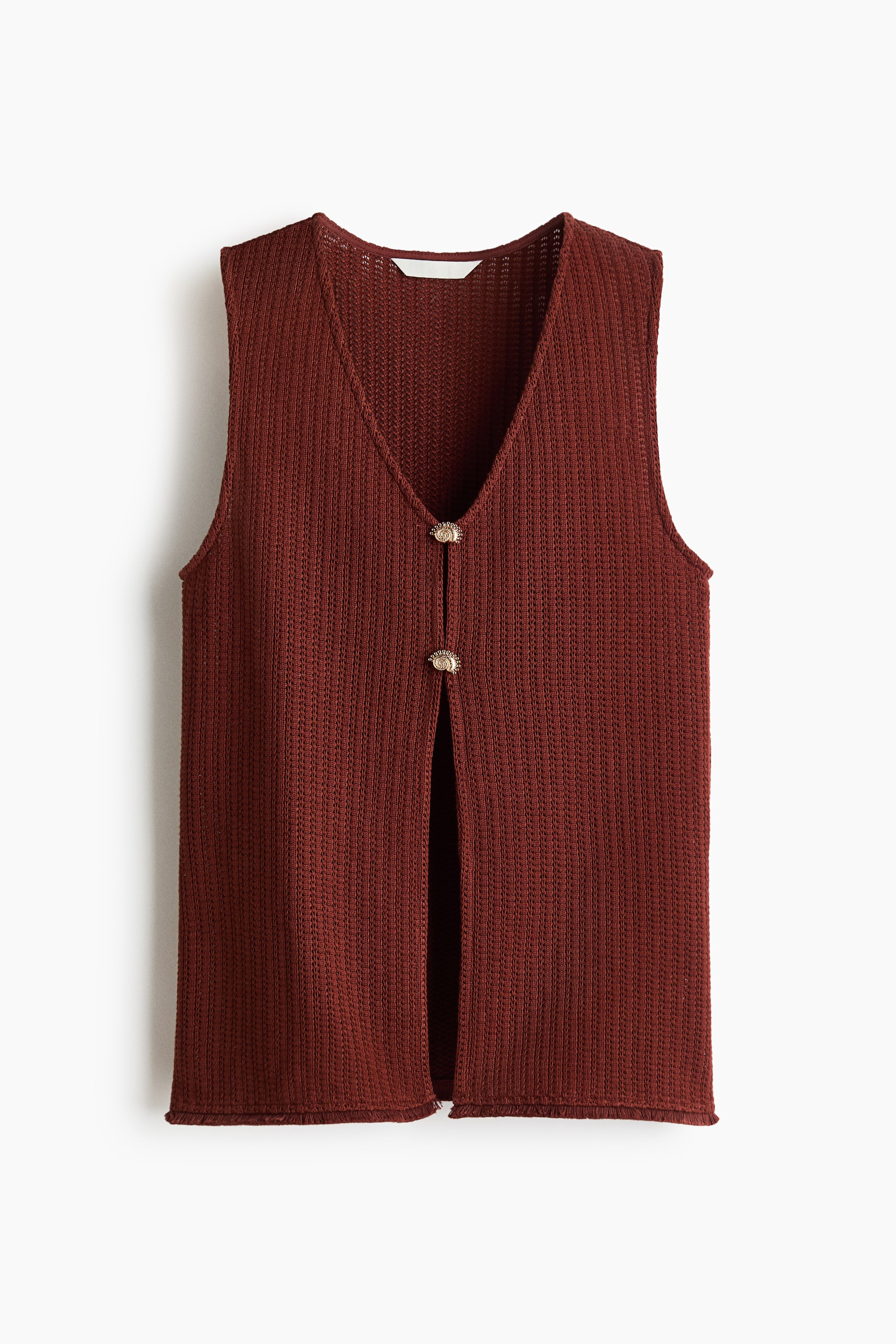 View larger image: A rust-coloured ribbed knit vest is shown FRONT. It features a deep V-neckline and two ornamental gold-toned buttons at the centre, creating an open-front split below.