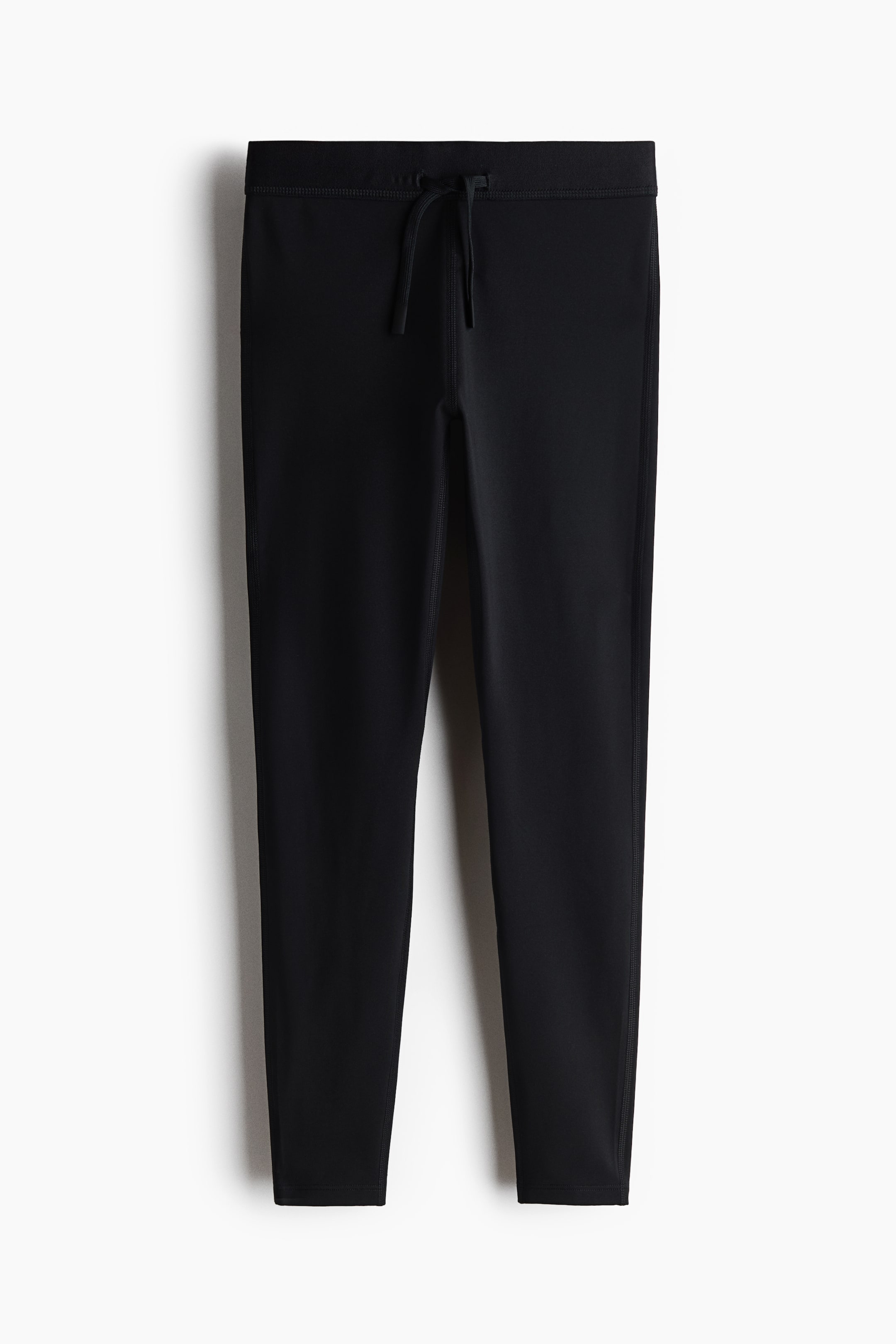 Größeres Bild ansehen: Schwarze Leggings werden von vorne präsentiert und verfügen über einen Bund mit Kordelzug und gebundenen Bändern. Die Leggings zeigen sichtbare Seitennähte und gesäumte Beinabschlüsse.