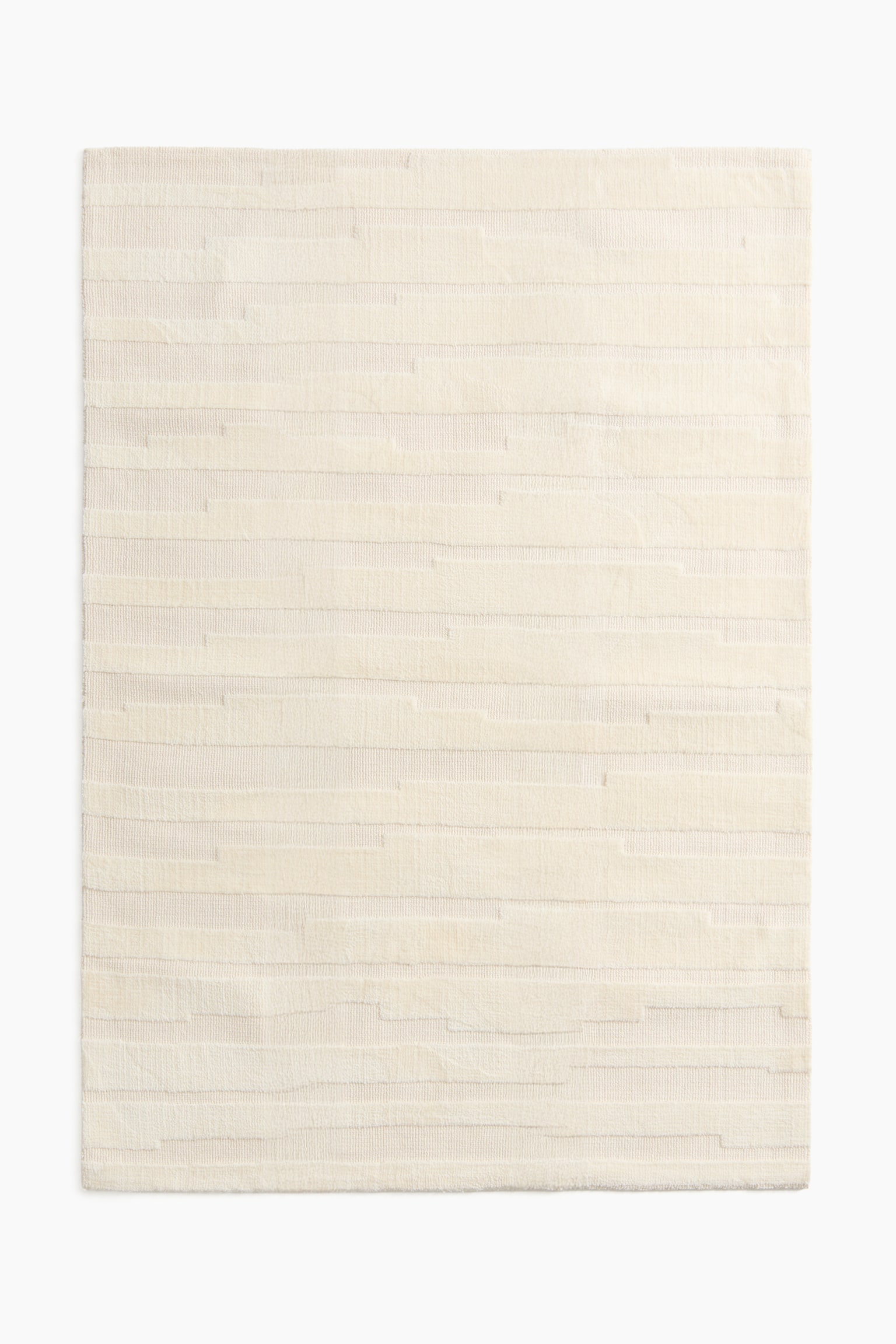 A woven rug showcasing a textured pattern, viewed from the front. It features horizontal bands with varying pile heights and textures, crafting an irregular striped design. - 1