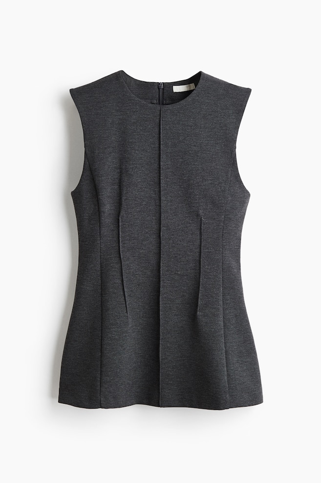 A dark gray sleeveless top is shown from the front, featuring a round neckline, structured, slightly extended shoulders, and a short zipper visible at the back neckline. Vertical seam lines are running down the center front, with two vertical pleats on each side creating a fitted and gently flaring silhouette. - 1