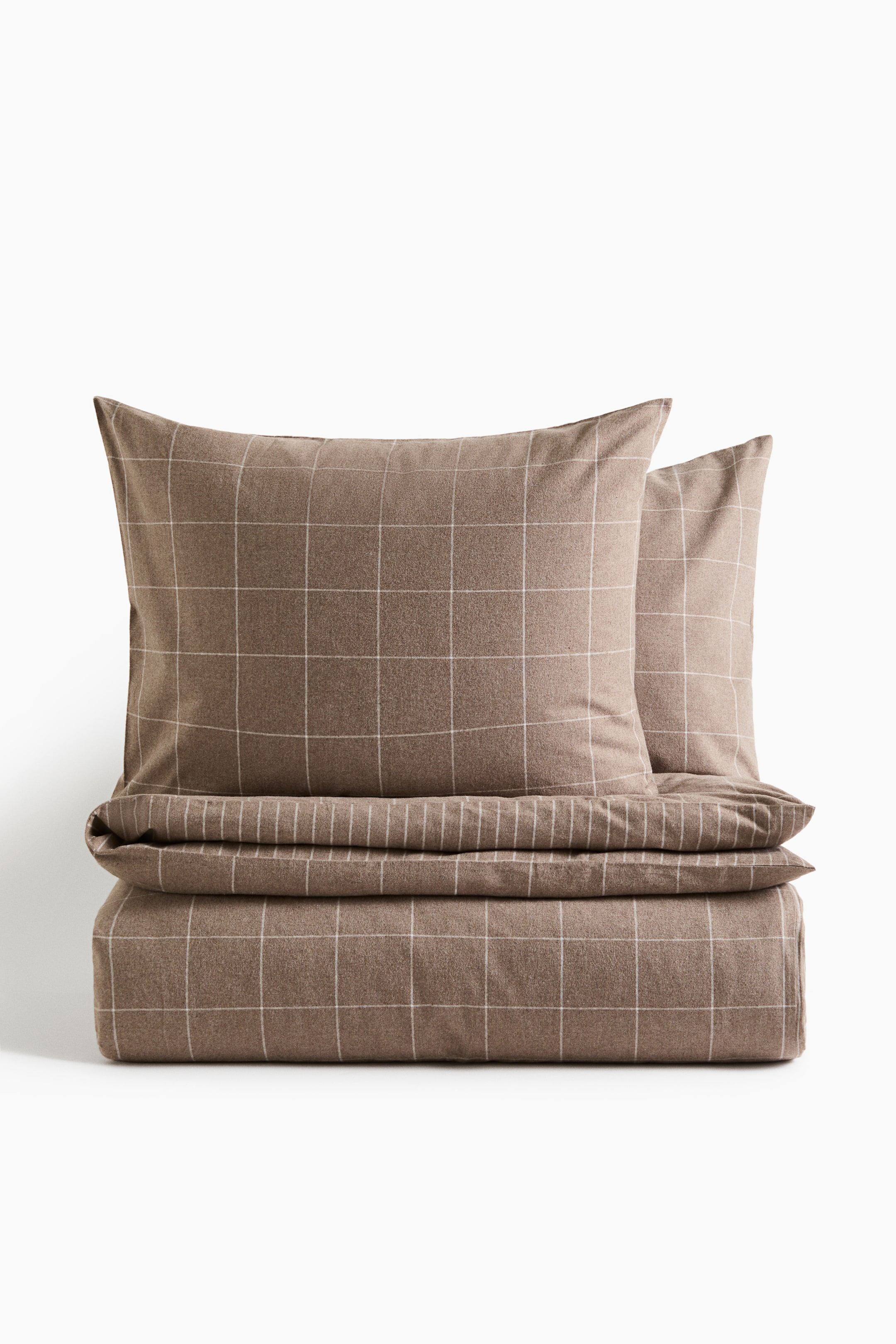 View larger image: A double duvet cover set in brown cotton flannel is showcasing a white windowpane grid pattern. The front-facing set features a neatly folded duvet cover at the base with two matching pillowcases standing upright behind it.