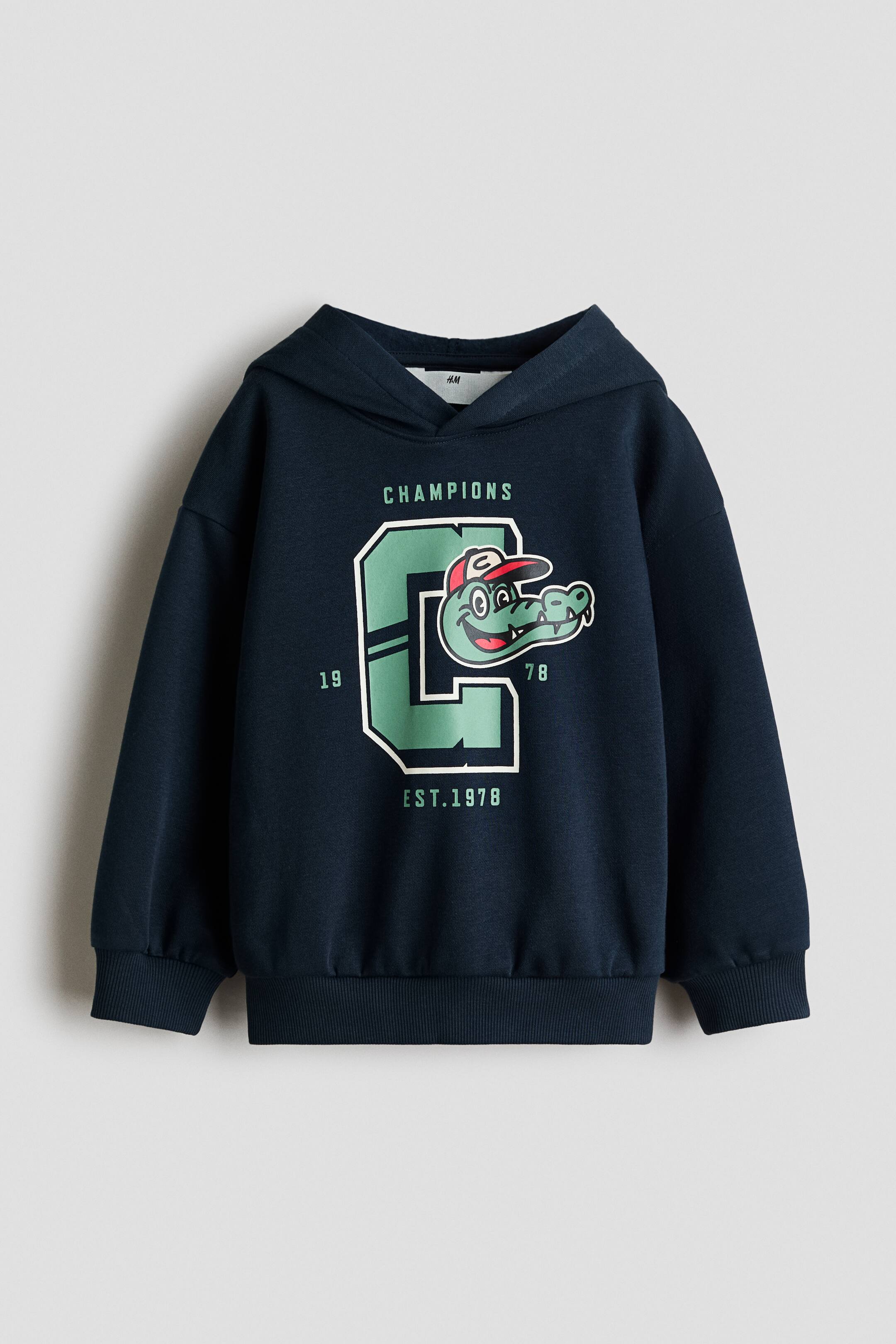 View larger image: A dark blue hoodie is facing front, showcasing a large green letter "C" with a white outline on the chest, into which a cartoon alligator head wearing a red cap is integrated. Above the "C", green text "CHAMPIONS" is displayed, with "EST. 1978" positioned below, and the numbers "19" and "78" placed to its sides. The hoodie features ribbed cuffs and a ribbed hem.