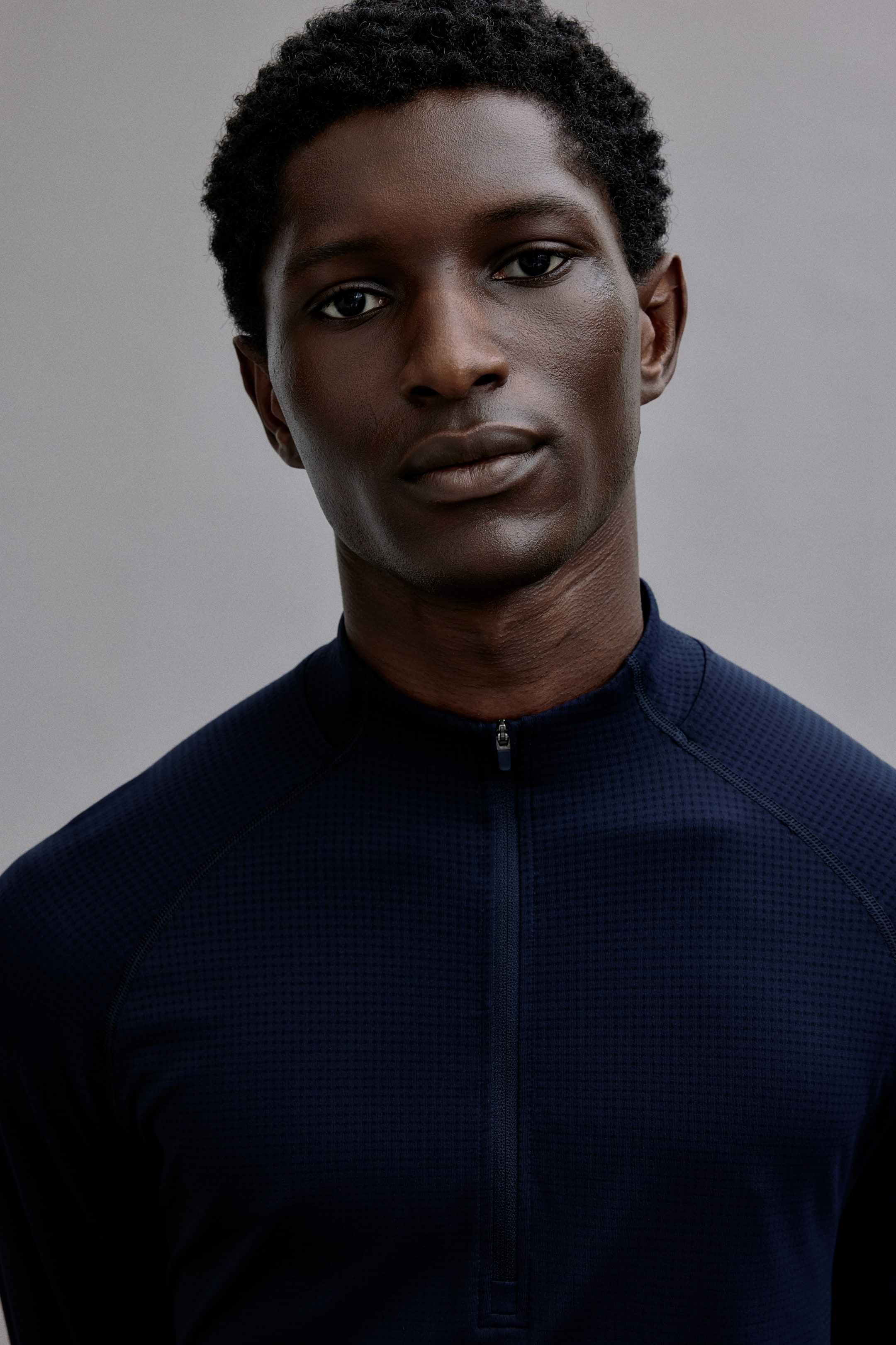 查看大圖: 這款海軍藍長袖上衣前方採用自立領延伸而出的 quarter-zip 開合。整件布料呈現細緻的格紋質感，並設計有外露的 raglan seams。