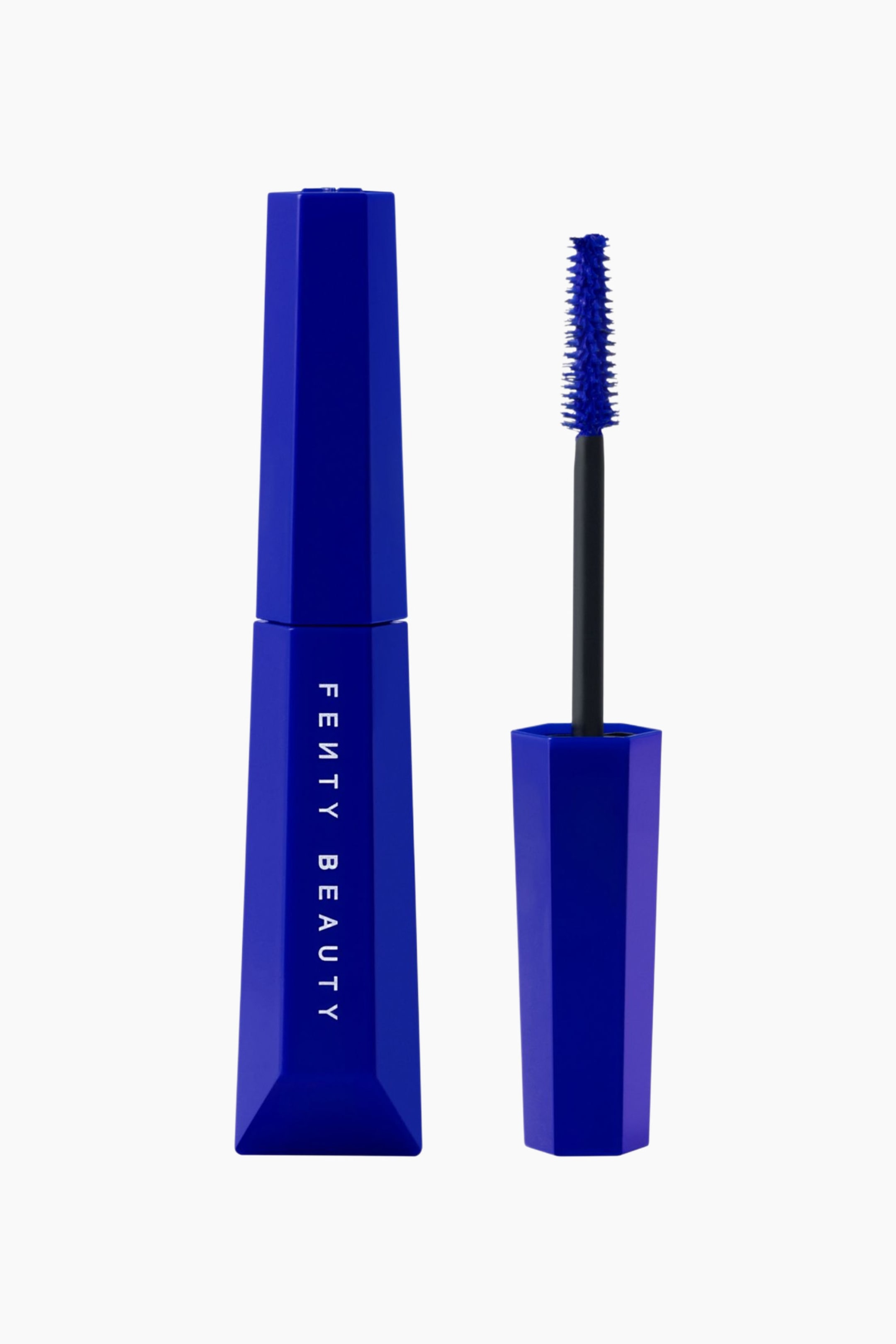 Visa större bild: Fenty Beauty Hella Thicc Volumizing Mascara står upprätt och visar upp en sluten, geometrisk hexagonal tub i livfull koboltblå med vit branding i vertikala linjer. Bredvid tuben står den avskruvade applikatorn, med ett matchande blått lock, ett svart skaft och en tät, avsmalnande borste täckt av klarrimascara i blått.
