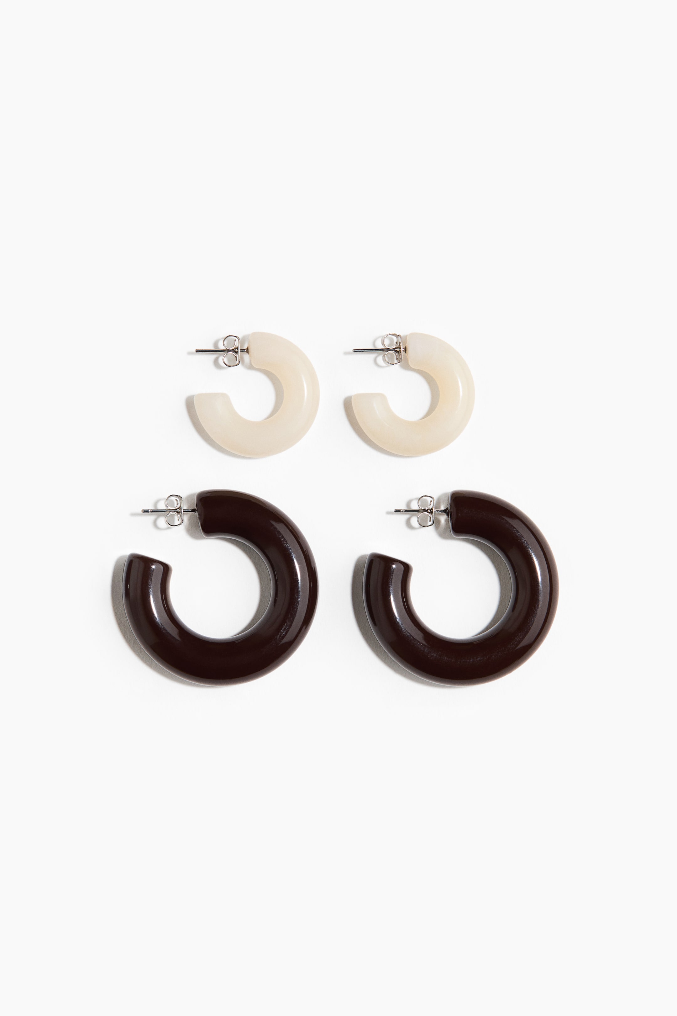 Agrandir l'image: Quatre boucles d'oreilles en forme de C sont posées à plat, montrant leur face avant. Deux boucles d'oreilles sont d'un blanc laiteux translucide, et deux sont d'un brun foncé brillant, toutes deux dotées de fermoirs à poussoir de couleur argentée.