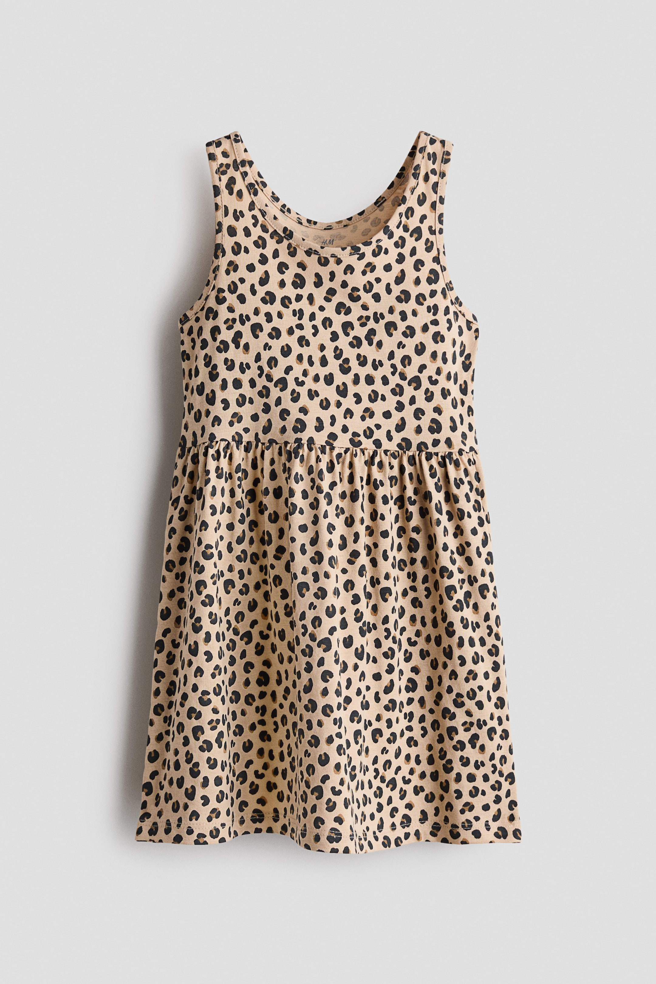 Agrandir l'image: Une robe sans manches à l'avant présente un motif léopard beige sur un tissu jersey doux, avec une couture froncée à la taille et une jupe légèrement évasée.