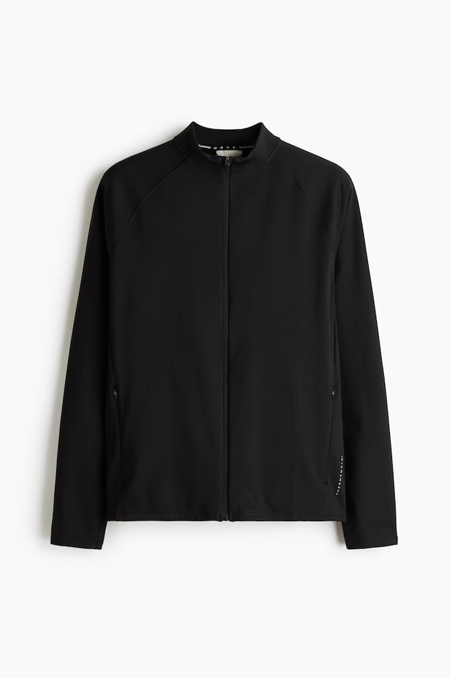 Eine schwarze Sportjacke ist frontal zu sehen und zeigt einen durchgehenden FrontreiÃverschluss, einen Stehkragen und RaglanÃ¤rmel. Die Jacke verfÃ¼gt Ã¼ber dezente Seitentaschen mit ReiÃverschluss sowie ein kleines vertikales weiÃes Logo nahe dem unteren linken Saum. - 1