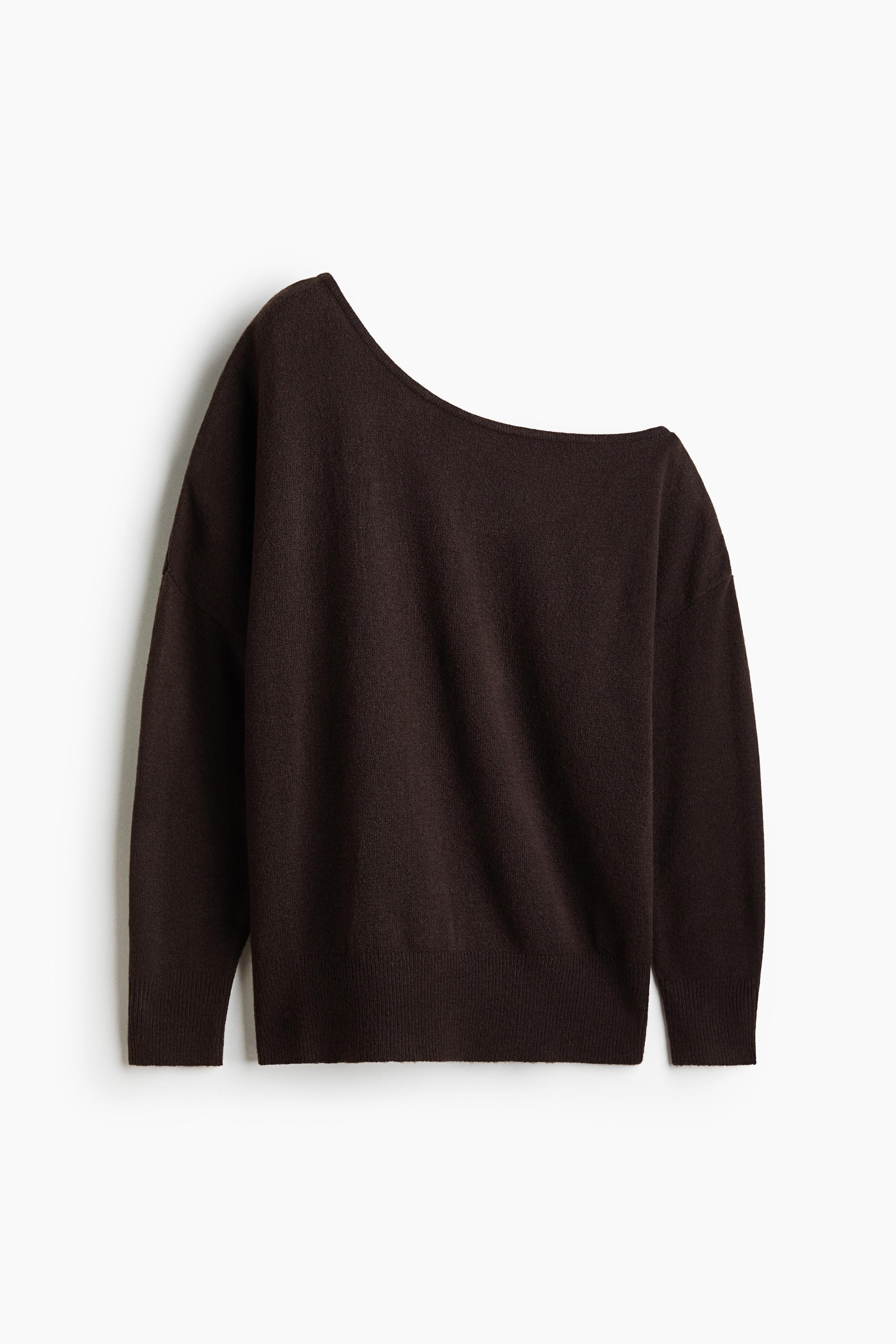 Ein dunkelbrauner Feinstrickpullover mit asymmetrischem One-Shoulder-Ausschnitt und Ã¼berschnittenen Schultern wird vom Model getragen. Der Pullover wird mit einer schwarzen Hose und einer dunkel gehaltenen Jacke kombiniert, die um die Taille gebunden ist, wobei das Model den Saum auf einer Seite leicht gerafft hÃ¤lt.
