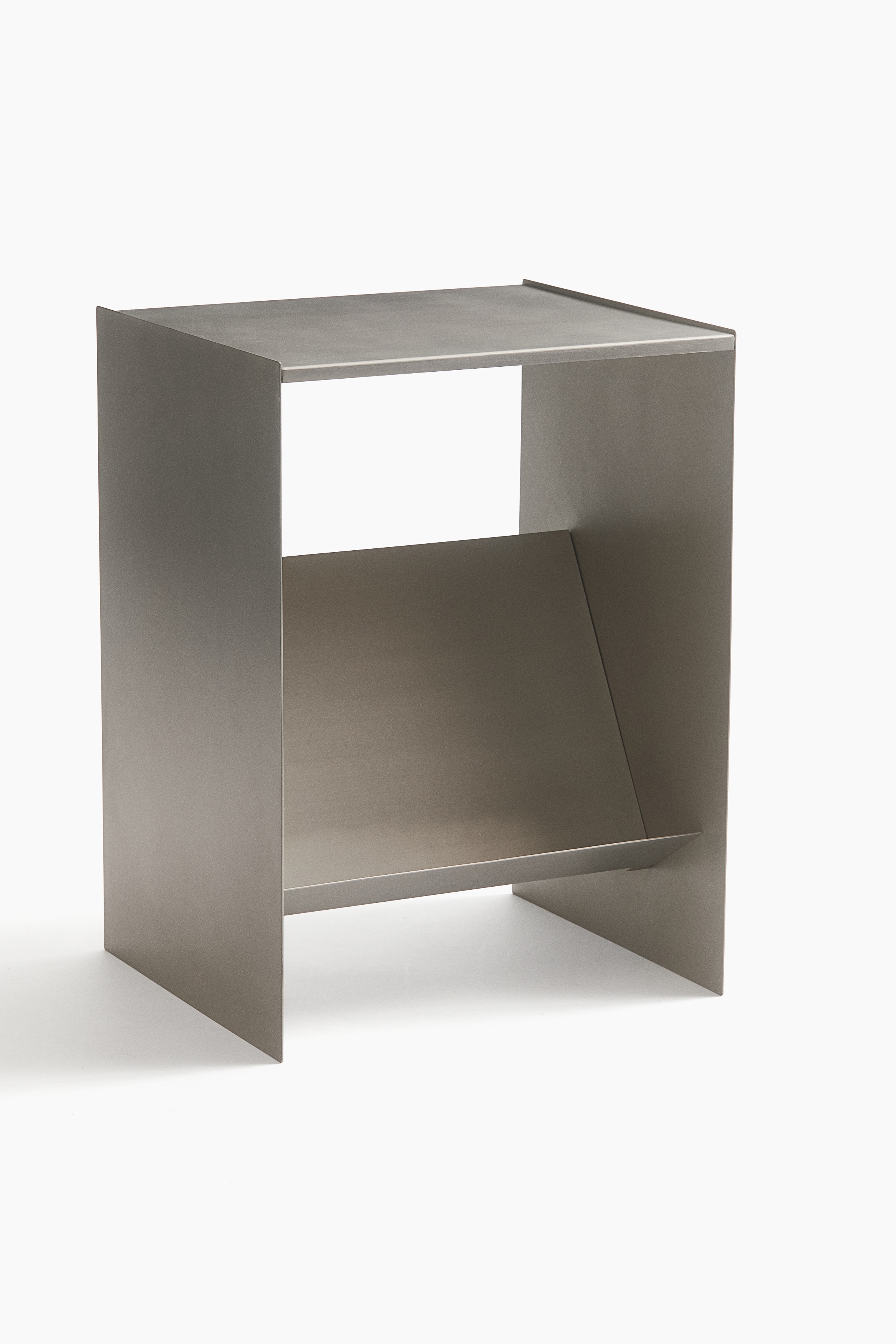 Une table dâappoint en mÃ©tal couleur bronze, au design gÃ©omÃ©trique, est prÃ©sentÃ©e de face, avec un plateau rectangulaire plat et une Ã©tagÃ¨re infÃ©rieure intÃ©grÃ©e qui supporte un livre carrÃ© recouvert de tissu.