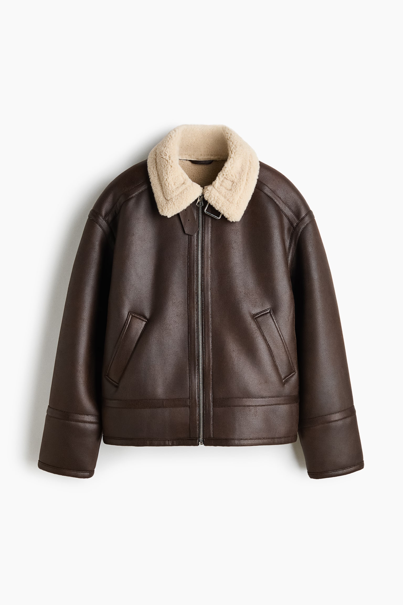 A dark brown aviator jacket is shown from the front, featuring a contrasting cream shearling collar and a central front zip fastening. It features dropped shoulders, angled welt pockets, and wide stitched details at the cuffs and hem. - 1