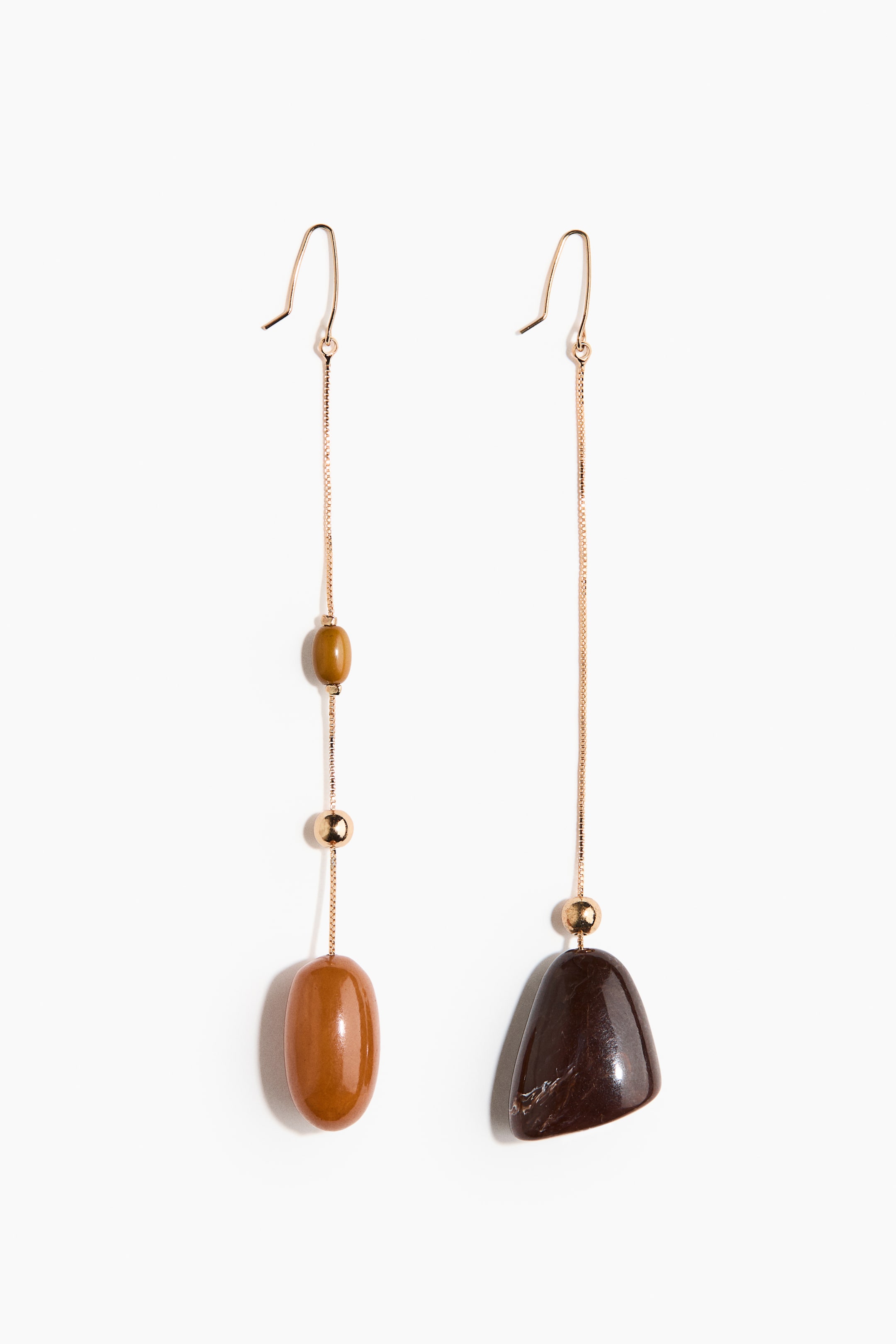 View larger image: Two asymmetrical dangle earrings are presenting gold-toned ear hooks connected to thin box chains, each featuring a small gold sphere. The left earring is displaying a glossy amber-orange elongated oval stone below an olive-green oblong bead, while the right earring is showing a glossy dark brown irregularly shaped stone with light veining.