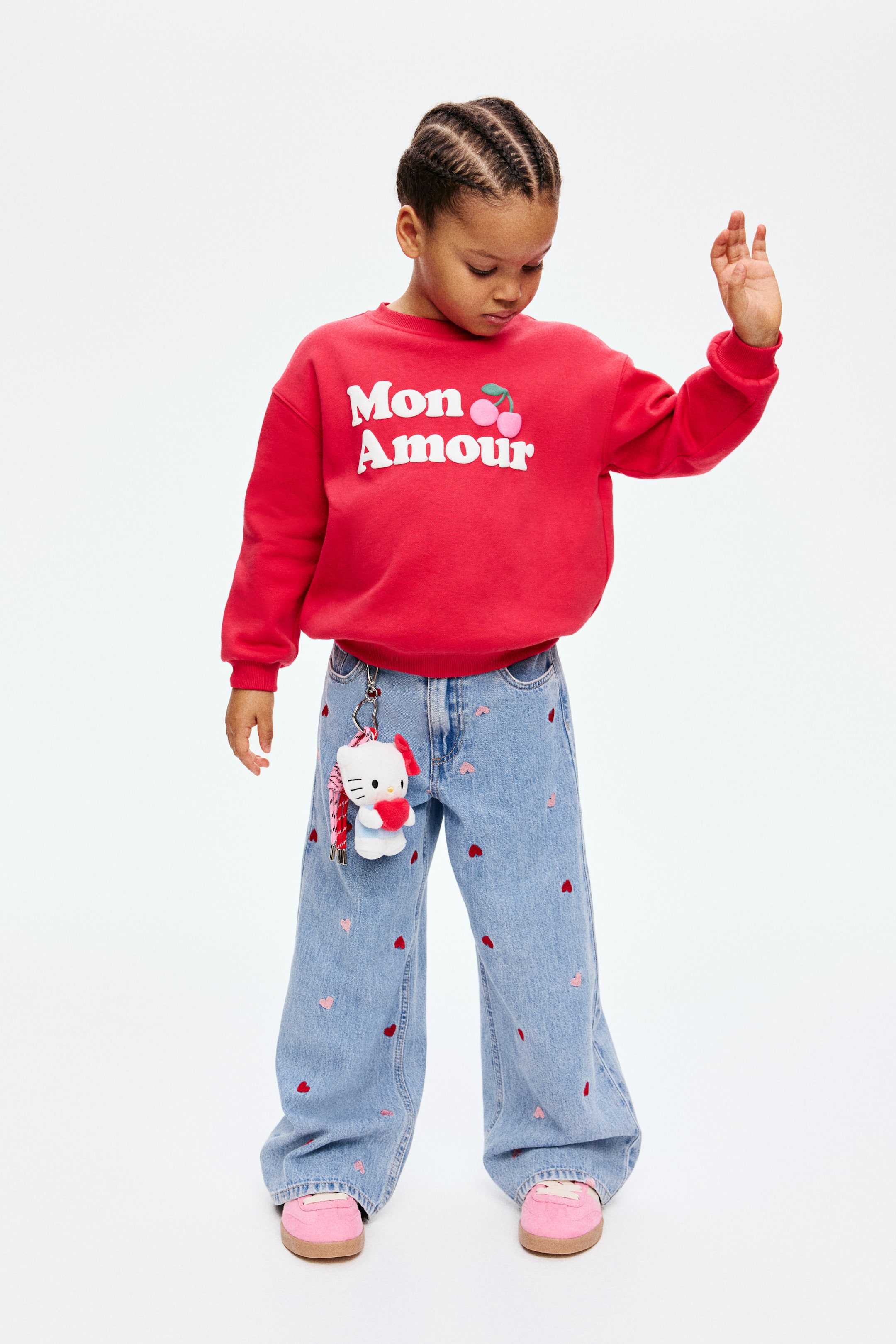 Ampliar la imagen: Los jeans de mezclilla azul claro están mostrando un motivo de corazones dispersos en rojo y rosa en la parte DELANTERA. Los jeans presentan un ajuste suelto a través de la cadera y el muslo, extendiéndose hacia piernas anchas.