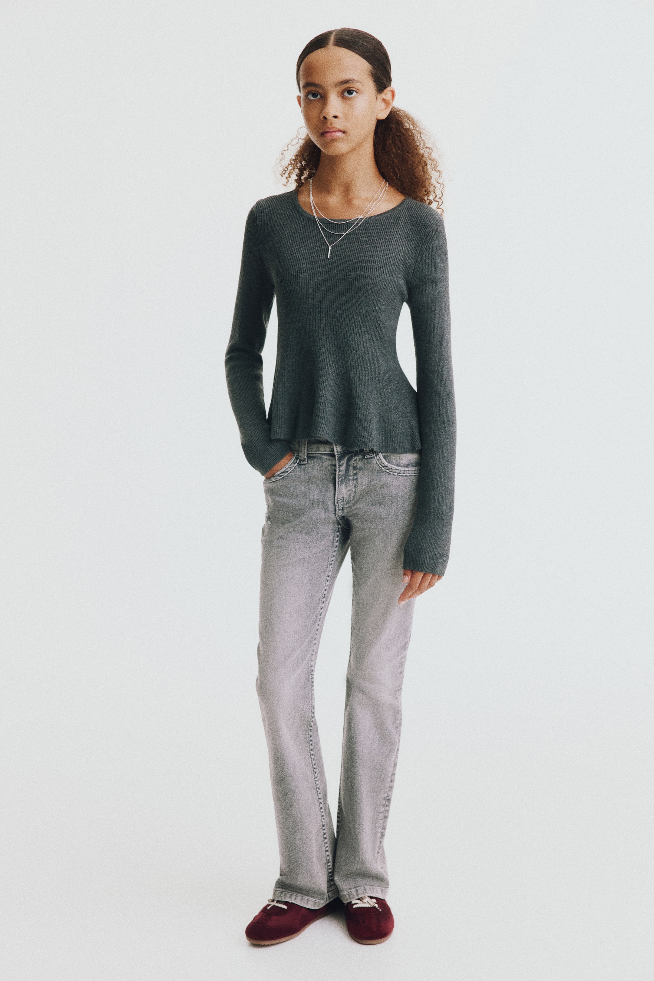 Se større billede: En model bærer lysegrå vaskede denimjeans set forfra, med lav talje, forlommer og en tætsiddende pasform over lårene, som går ud i bootcut ved benåbningerne. Jeansen har diskrete whiskering-effekter og slidte detaljer hen over hofterne.