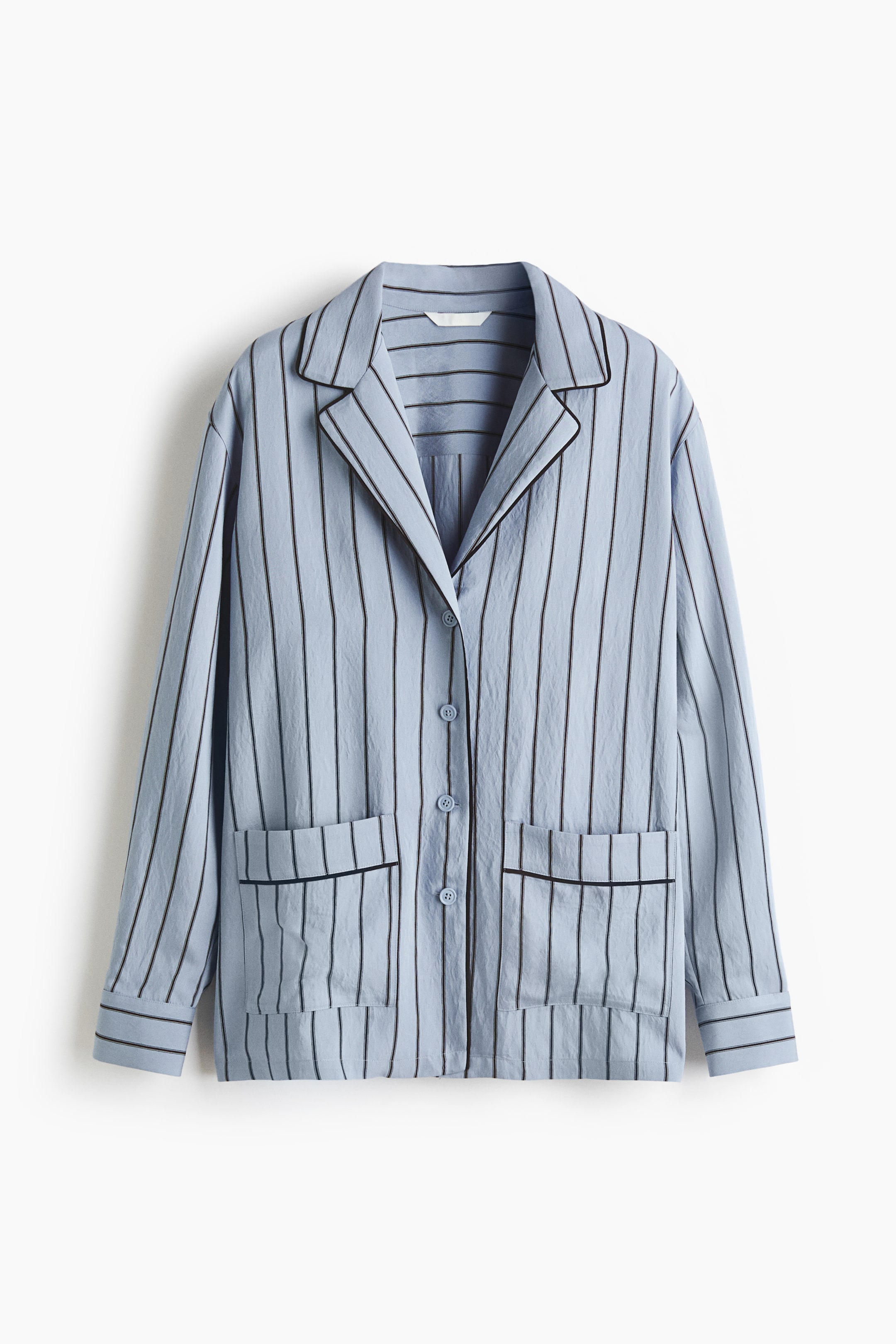 View larger image: A light blue pyjama top showcasing a vertical black stripe pattern and black piping accentuating its notch lapels, button-front placket, two lower patch pockets, and sleeve cuffs. Light blue buttons fasten the front closure.