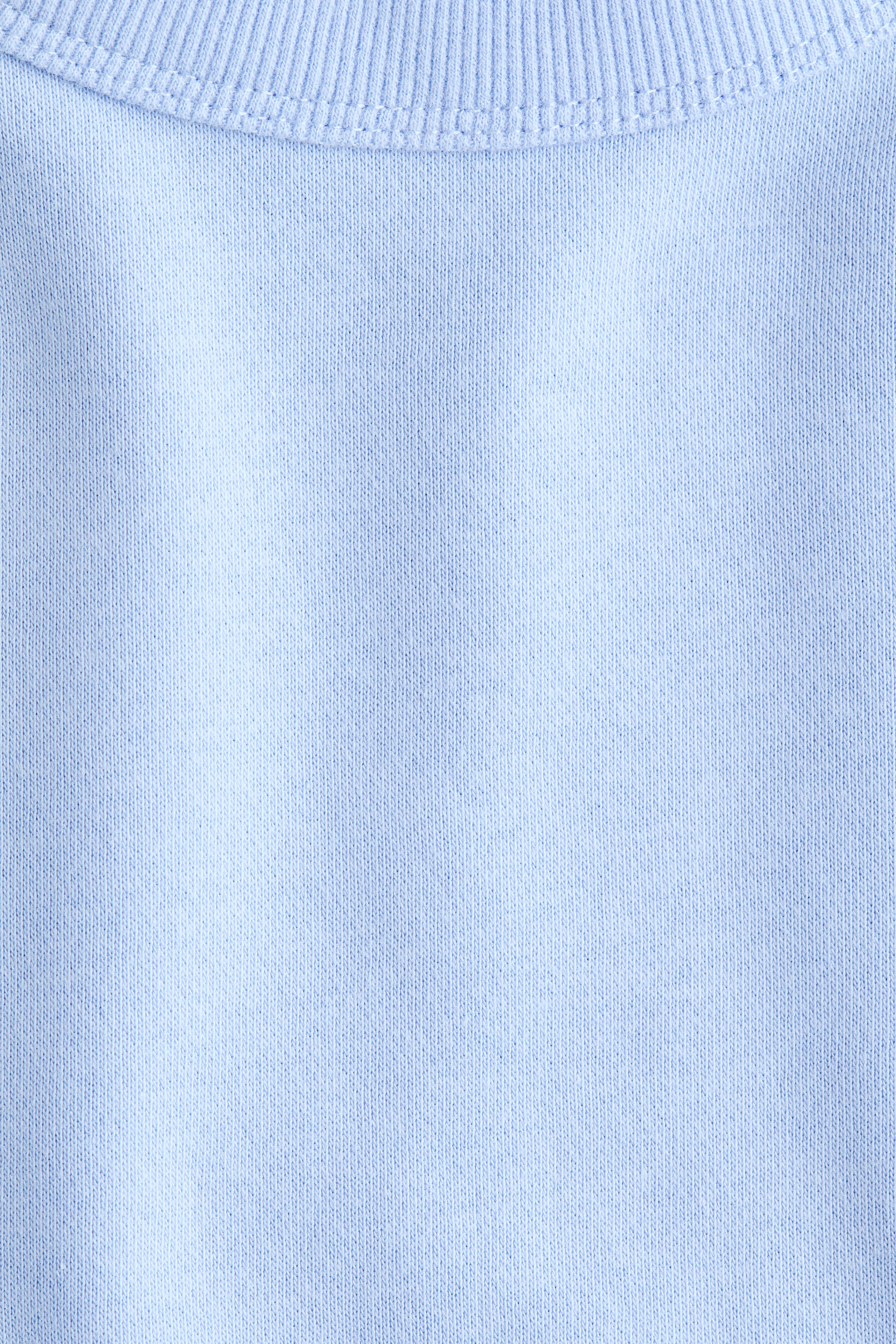 Agrandir l'image: Un vêtement tricoté bleu clair présente une vue de FACE de son tissu principal, qui montre un col côtelé en haut avec une couture double visible le fixant au corps du vêtement.