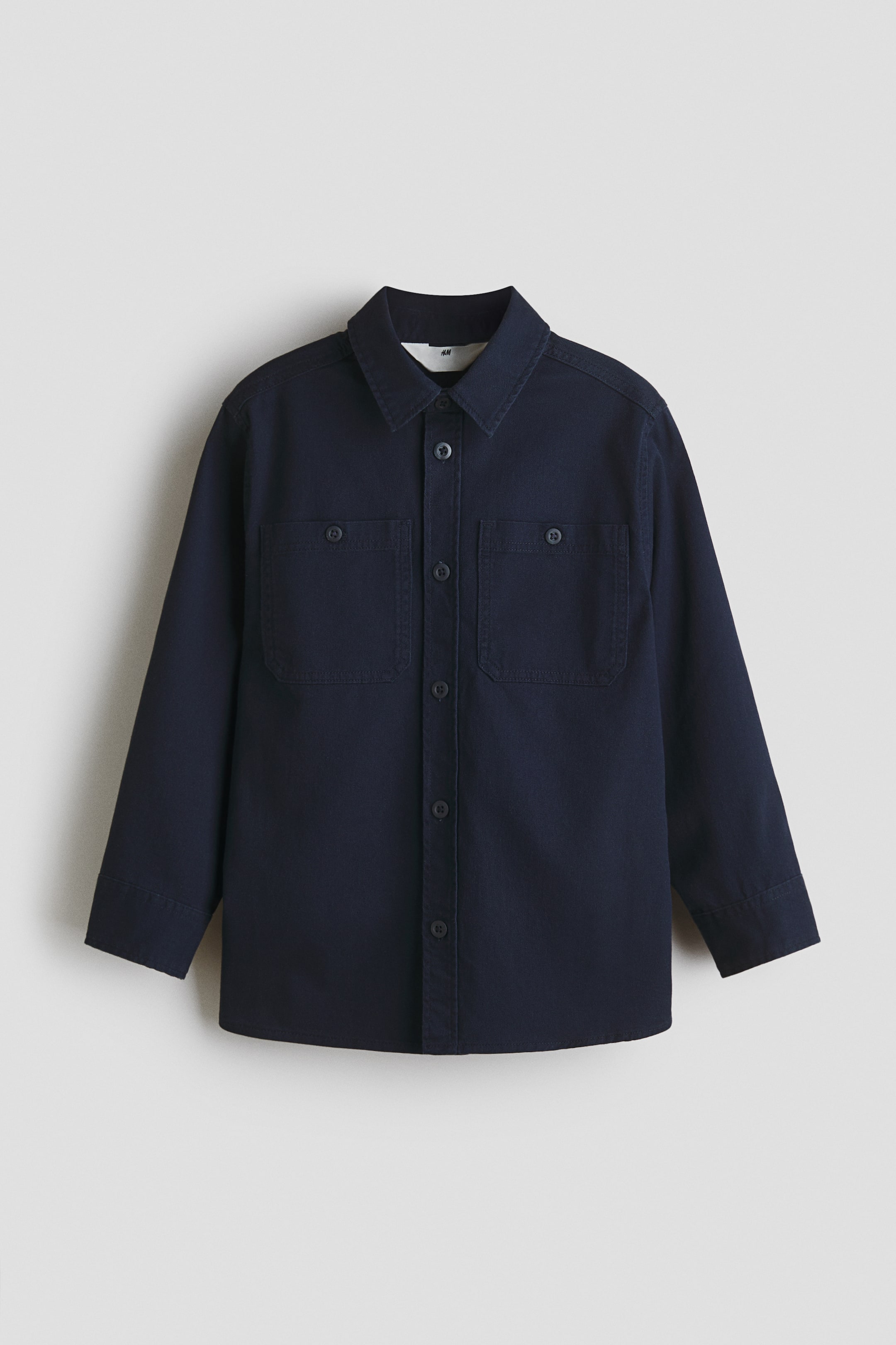 View larger image: A dark blue shirt, shown from the FRONT, features a classic collar, long sleeves, a full button placket with dark buttons, and two buttoned chest pockets.