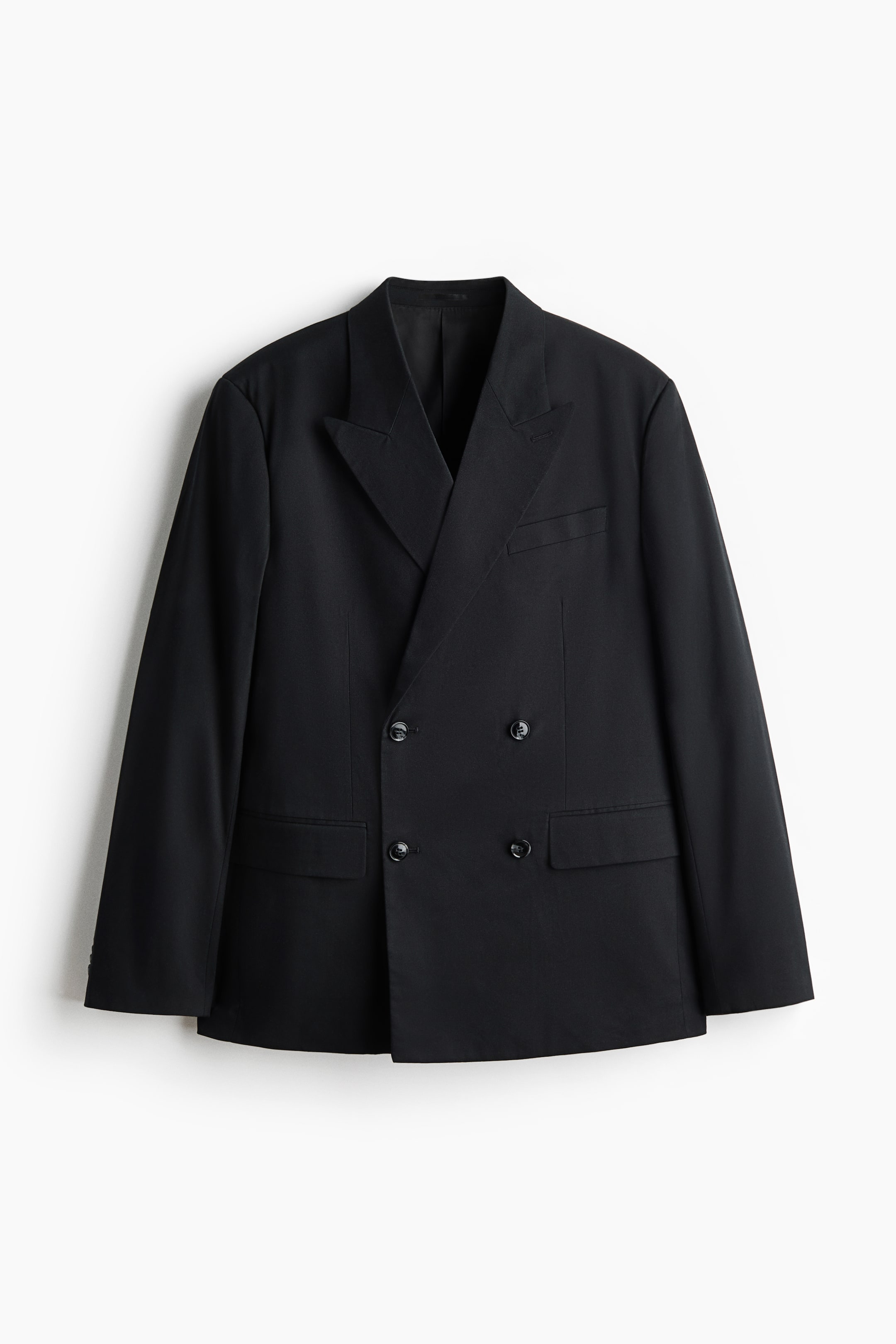 View larger image: A black double-breasted jacket is hanging front-facing, showcasing peak lapels with a decorative buttonhole on the left side. It features a chest pocket on the left, two flapped jetted front pockets, and four dark buttons on the front closure, offering a relaxed silhouette.