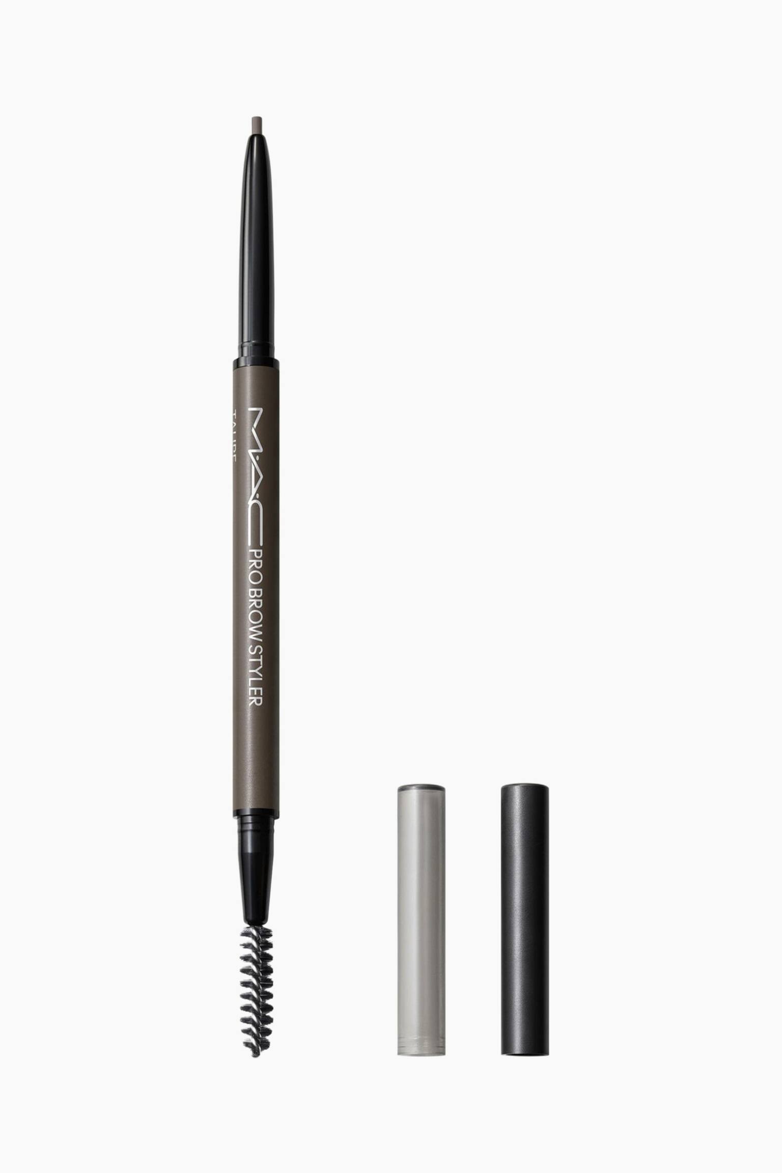 Pro Brow Styler-øjebrynsblyanten står lodret og har et dobbeltsidet design med en fin, udtrækkelig blyant i den ene ende og en sort spoolie-børste i den anden. Den taupefarvede midtersektion har hvid branding, og to separate cylindriske hætter i sølv og sort står oprejst ved siden af.