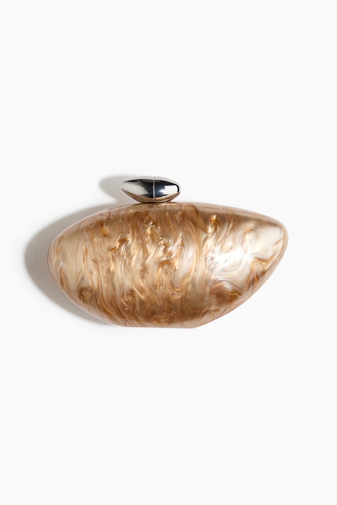 Une pochette asymétrique orientée vers l'avant présente une construction en plastique marbré et nacré avec une finition brillante. Elle est dotée d'un fermoir de sac allongé de ton argenté sur le dessus. - 1