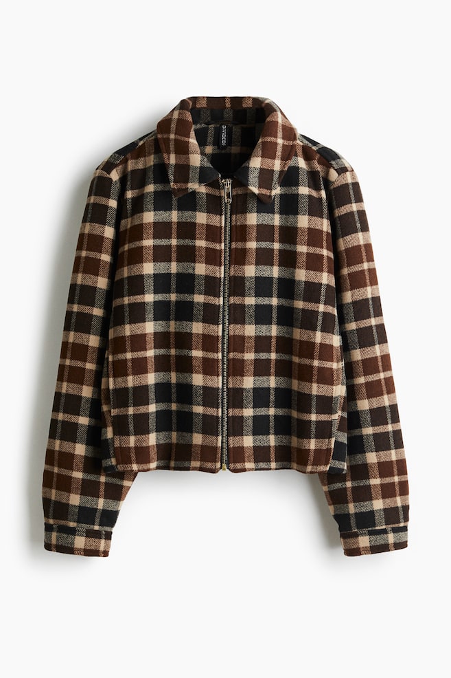 A short jacket is being presented from the FRONT, featuring a brown, black, and beige plaid pattern in a sturdy weave. It is designed with a collar, a zip closure running down the front, discreet side pockets, and cuffs that are displaying a slit and a press-stud. - 1