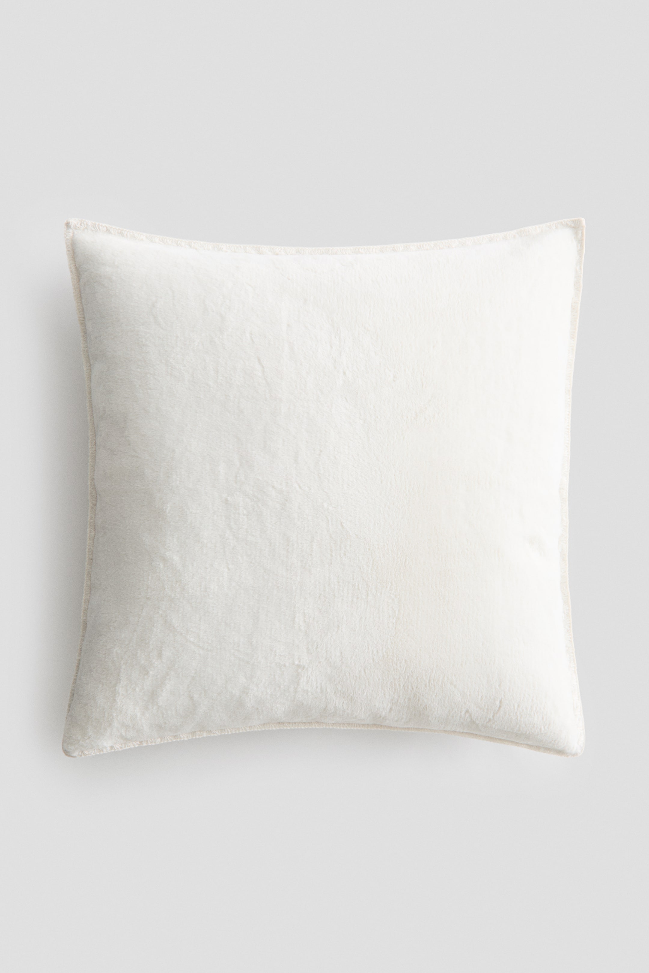View larger image: A square off-white cushion is facing front, displaying a soft, plush-textured fabric surface and a subtly stitched border along its edges.