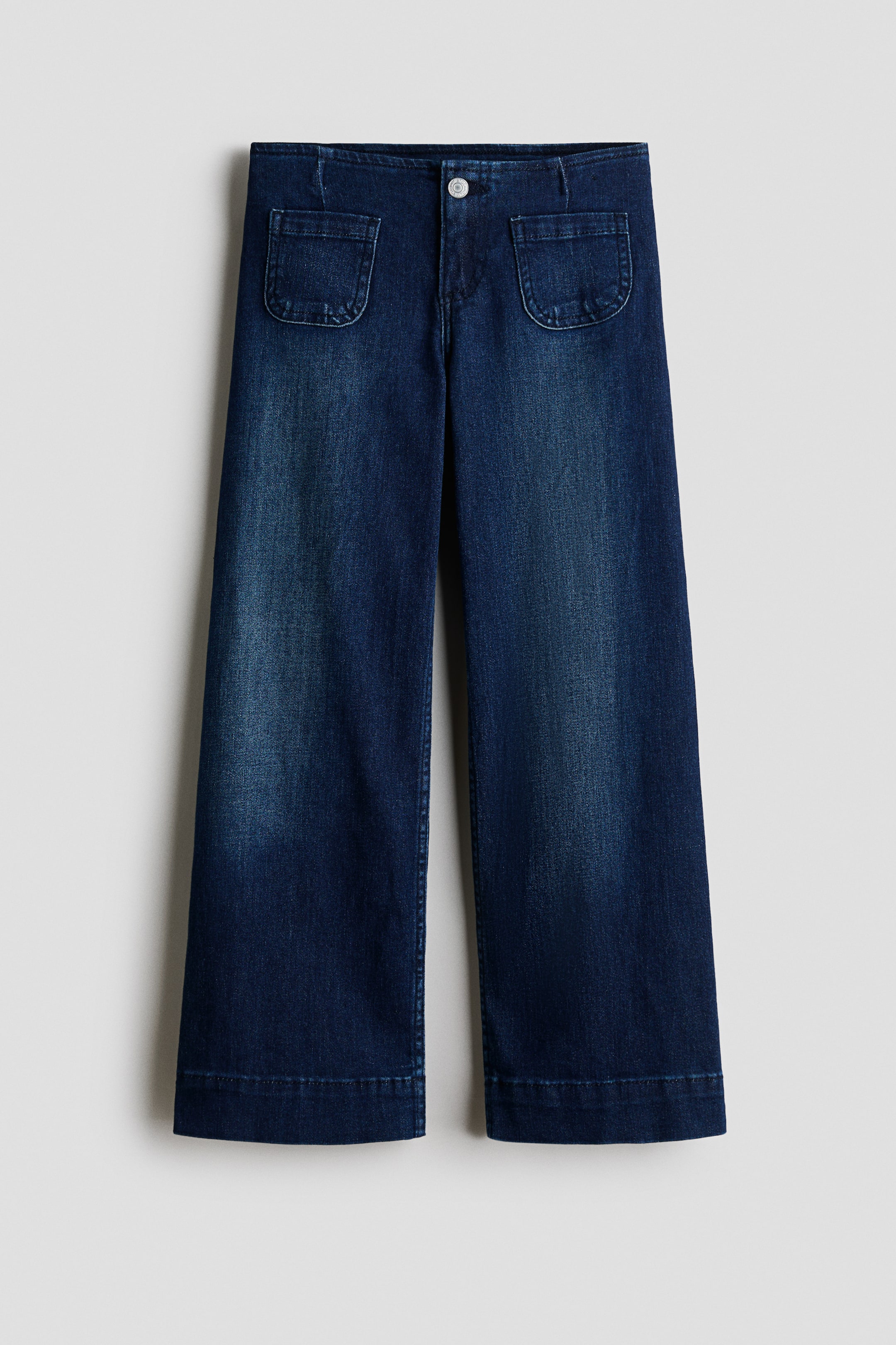 View larger image: Dark blue jeans are shown in a front view, featuring a button and zip fly. They are designed with rounded patch pockets on the front, and their slim fit through the hip and thigh flares into wide legs.