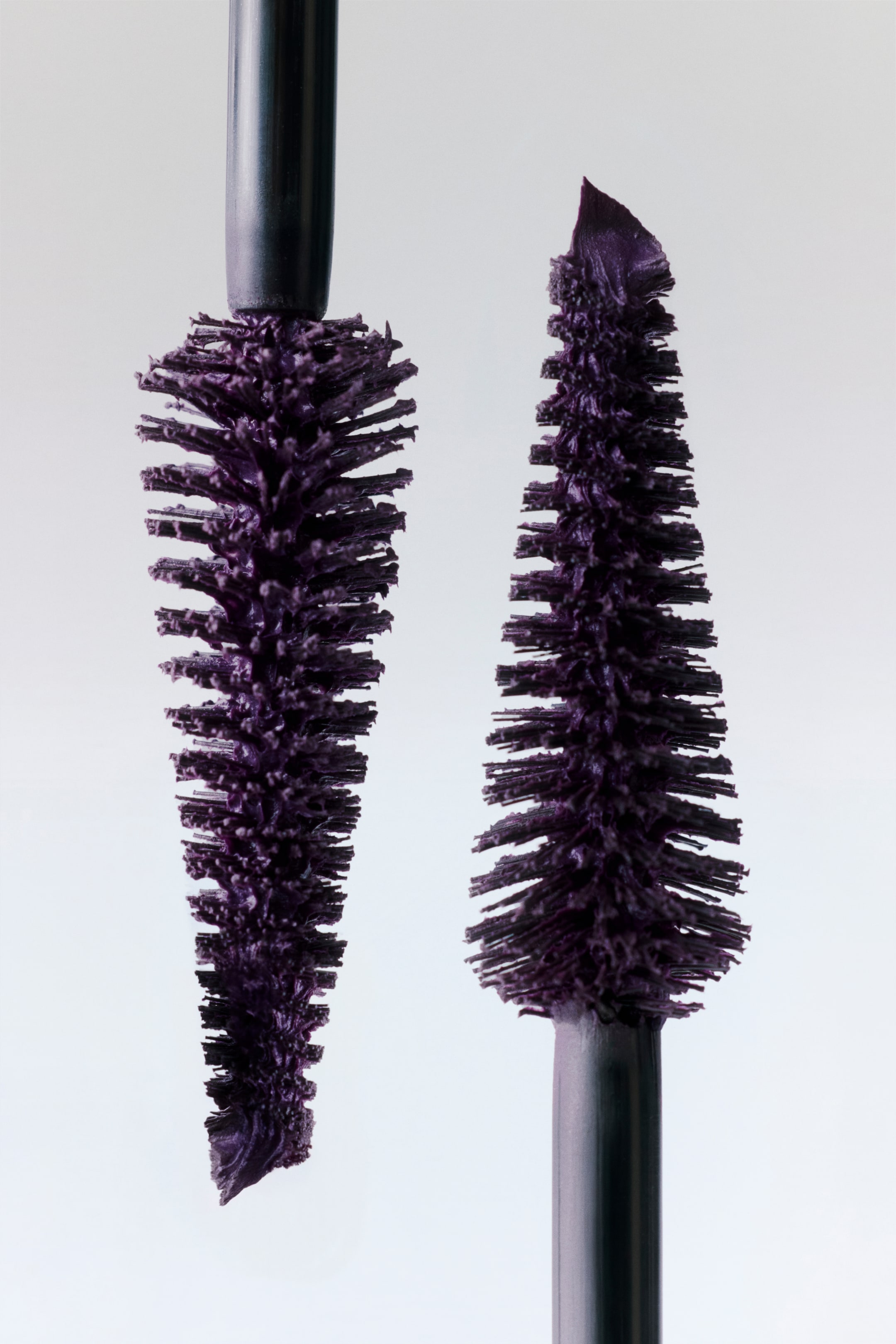 Visualizza immagine più grande: Due scovolini per mascara viola sono posizionati in verticale, mettendo in mostra le loro testine distintive. Lo scovolino a sinistra presenta una testina cilindrica, mentre quello a destra mostra una testina conica con una punta affilata.