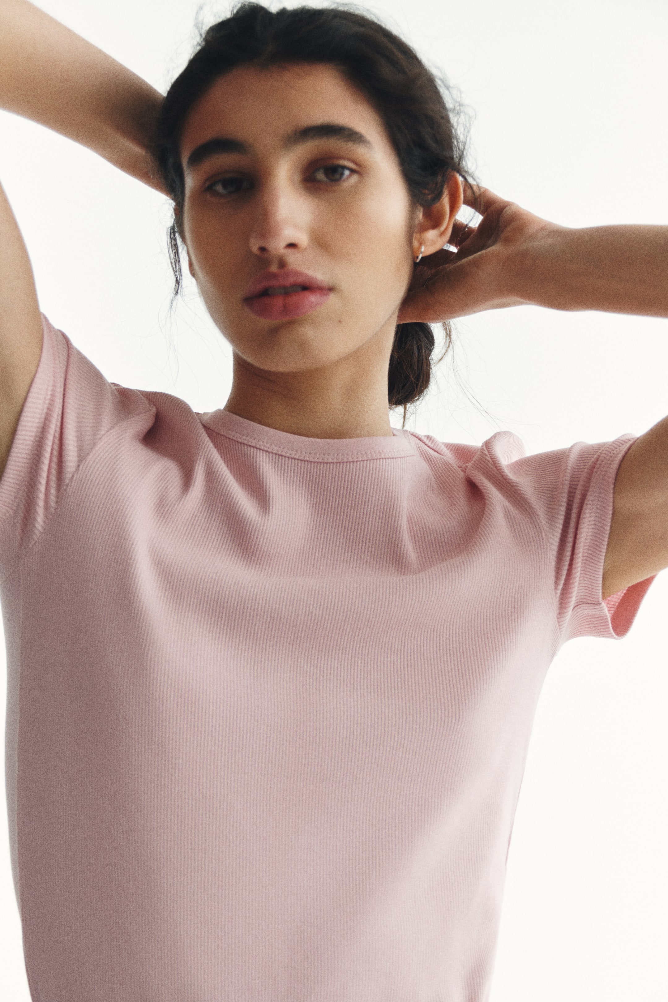 View larger image: A light pink ribbed knit crew neck top is displayed from the front, showcasing short sleeves with ribbed cuffs.