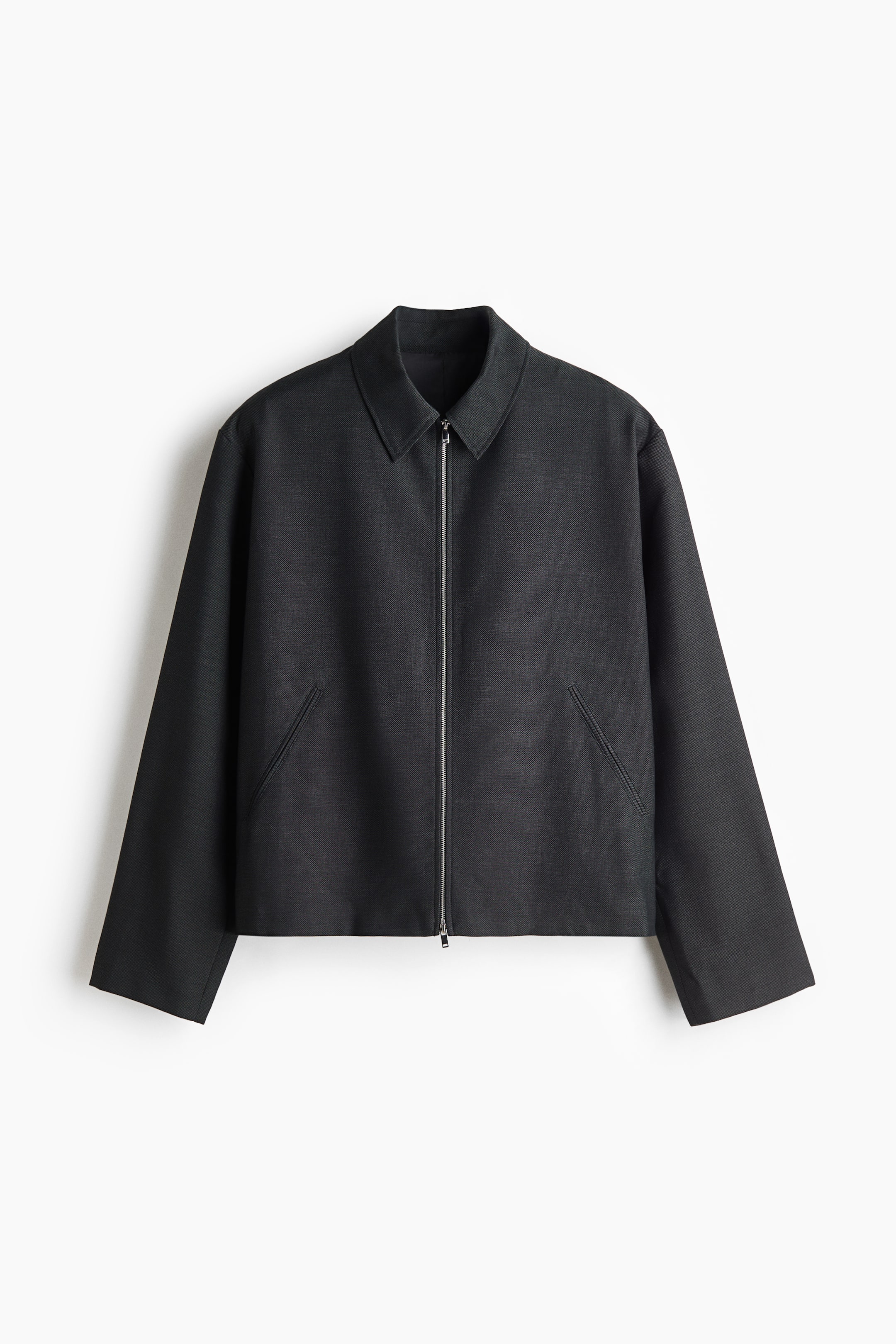 View larger image: A dark gray zippered jacket is shown from the front, highlighting a clean, structured silhouette with a point collar and a full-length silver metal zipper. It features two diagonal welt pockets and long sleeves with simple, straight cuffs.