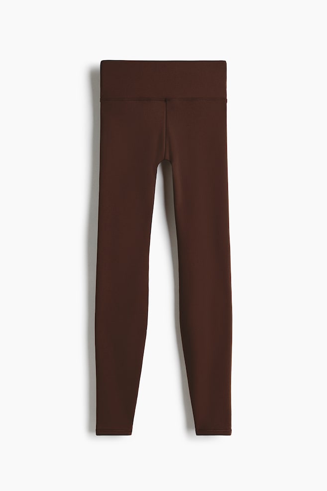 Brown leggings are displayed from the front, featuring a wide, high waistband and form-fitting legs with a simple ankle hem. - 1