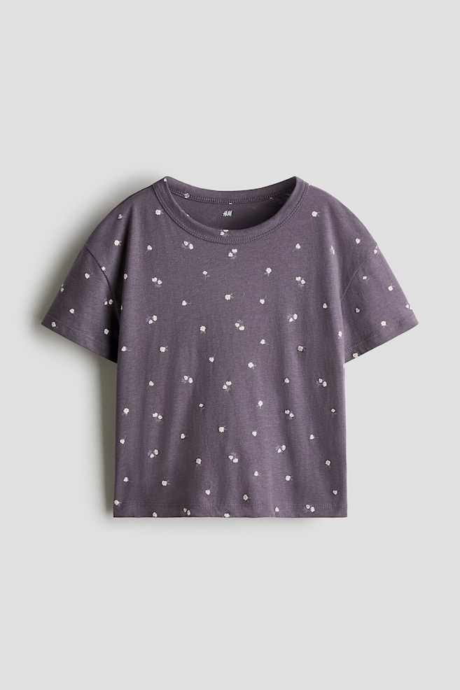A dark purple cotton jersey T-shirt is front-facing, showcasing a small all-over white floral print, a round neck, dropped shoulders, and short sleeves. - 1