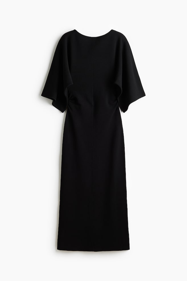 A black, calf-length knit dress is hanging facing forward, featuring a delicate boat neckline and wide, draped short sleeves. A vertical seam runs down the centre front, and gathered side seams create a draped effect at the waist. - 1