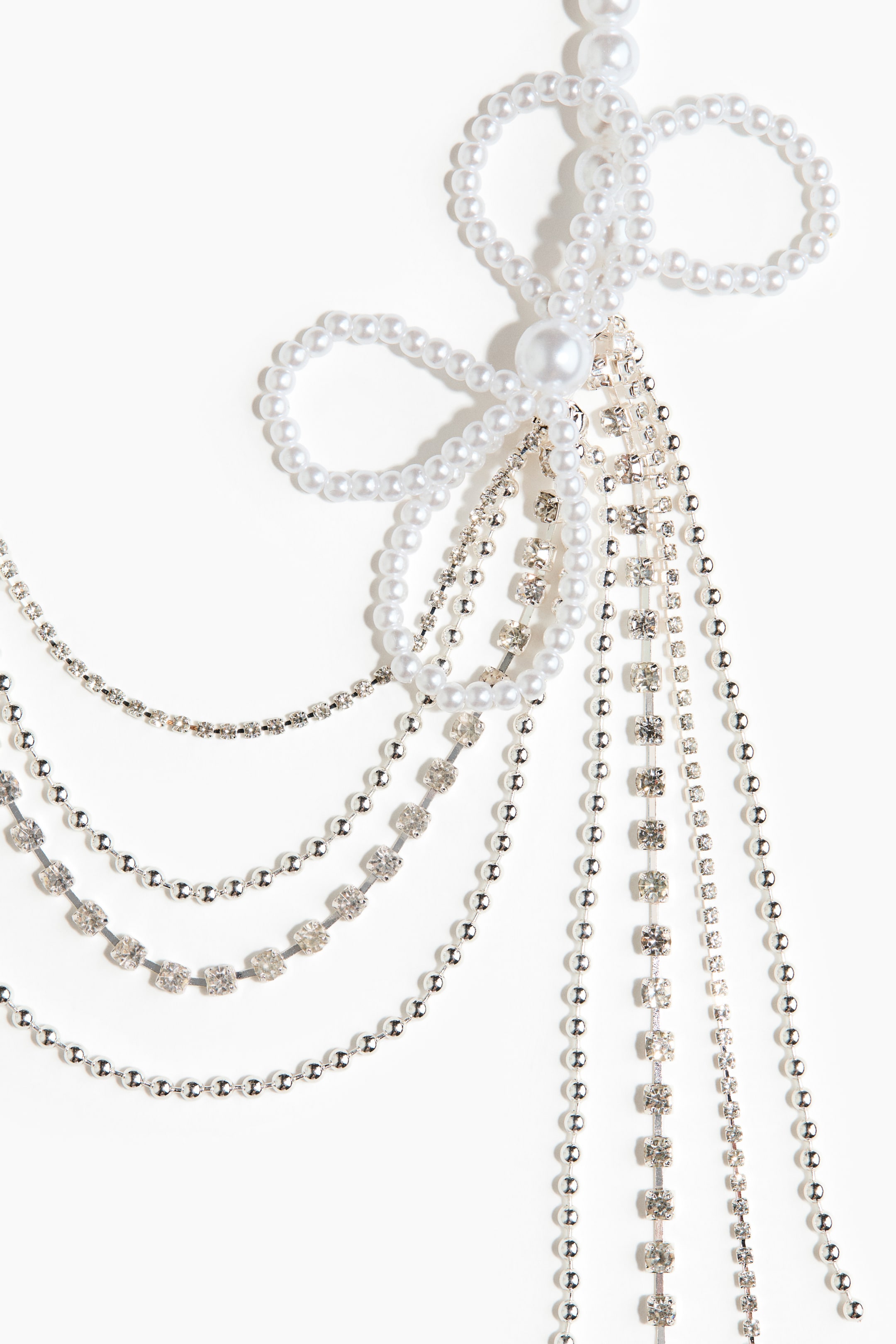 Ampliar la imagen: Un accesorio de múltiples hilos presenta perlas blancas y piedras de imitación transparentes. Las hebras de perlas forman un diseño similar a un lazo en la parte superior, centrado por una perla más grande, mientras que varias cadenas de perlas y piedras de imitación caen hacia abajo.