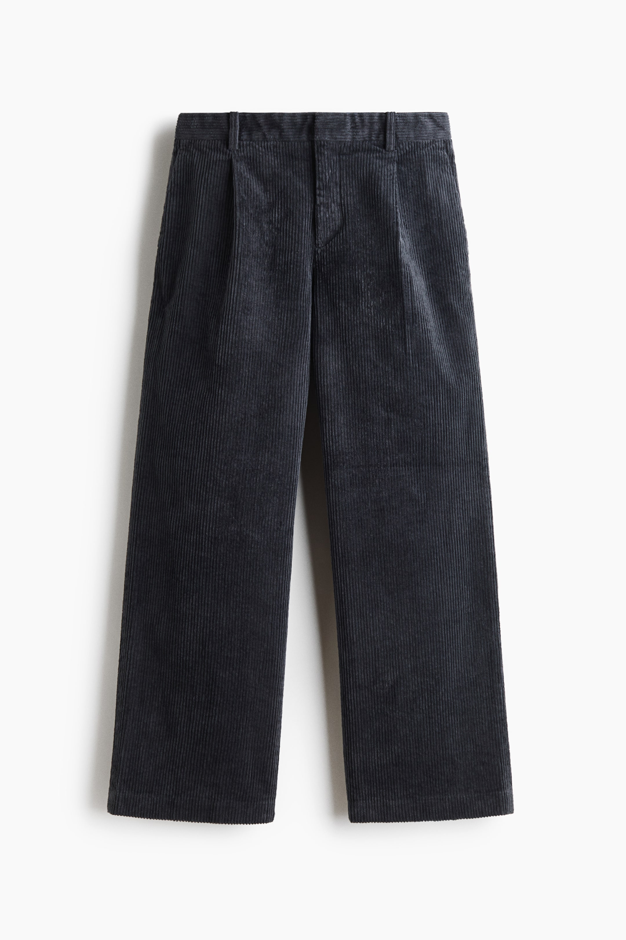 Visualizza l'immagine ingrandita: Un paio di pantaloni in velluto a coste grigio scuro è mostrato frontalmente, con silhouette a gamba larga, pieghe sul davanti e cintura con passanti per la cintura. I pantaloni presentano un tessuto testurizzato a coste e tasche laterali oblique.