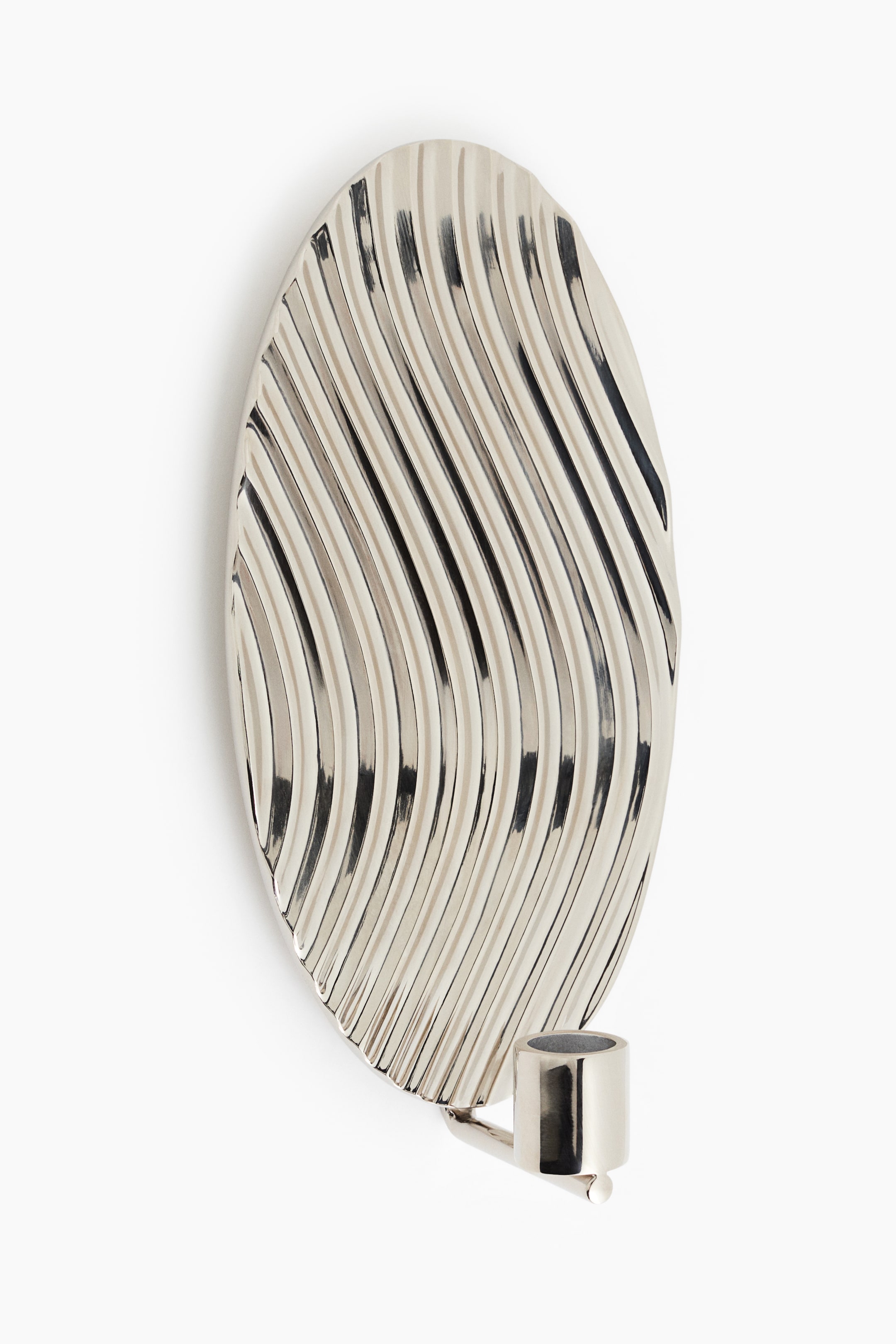 View larger image: A silver-toned wall sconce candle holder, facing front, is displaying an elongated oval backplate with a highly reflective, wavy ribbed texture. A small, polished cylindrical candle cup is extending forward from the bottom of the backplate.