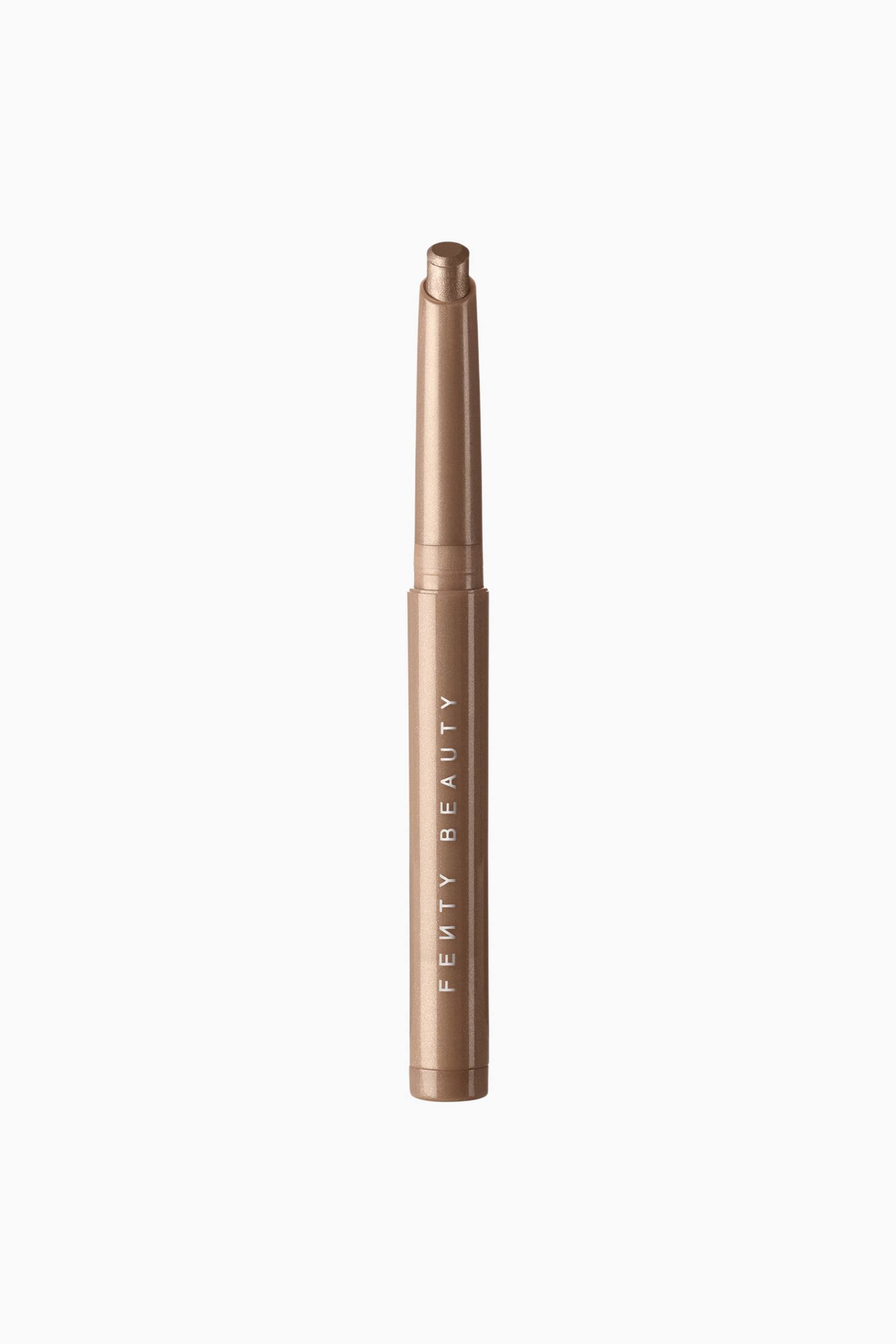 Se større billede: Shadowstix Longwear Eyeshadow Stick står lodret og fremviser sin metalliske, skinnende bronze-taupe nuance. Den farvematchede cylindriske hylster viser "FENTY BEAUTY"-logoet trykt lodret i hvidt, mens den uafdækkede top afslører den afrundede cremeøjenskyggetip.