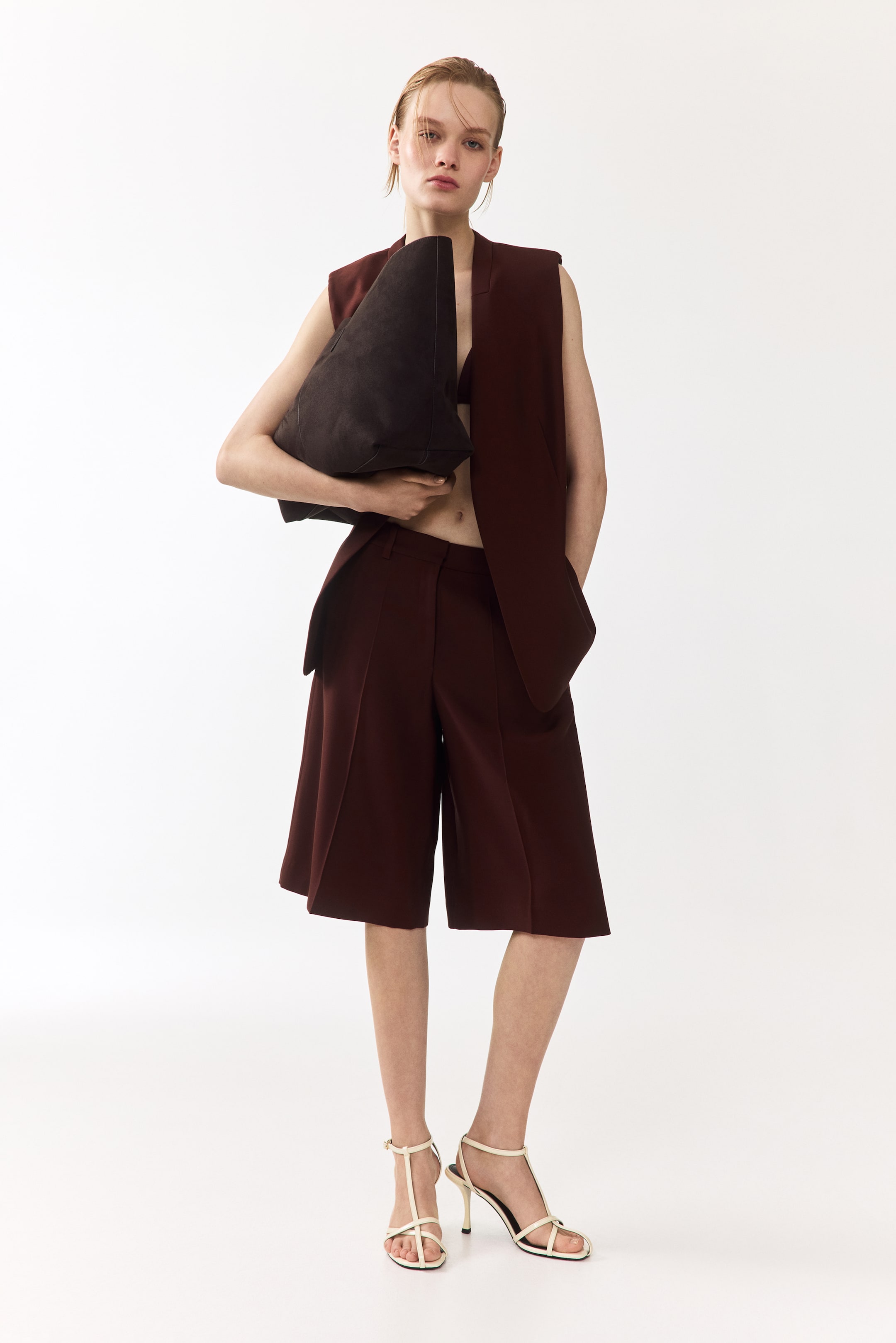 View larger image: A rich burgundy sleeveless vest is front-facing, showcasing distinct notch lapels and a structured, tailored design that extends beyond the waist.