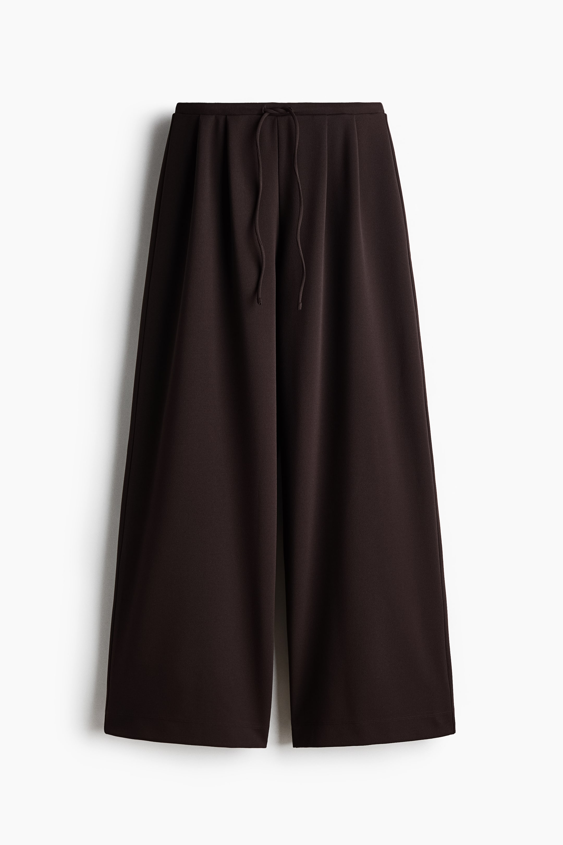 Größeres Bild ansehen: Die Hose ist dunkelbraun und zeichnet sich durch einen weiten Bein-Schnitt aus. Der vordere Bund ist elastisch und zeigt eine sichtbare Kordel, die in einem einfachen Knoten gebunden ist. Der Stoff wirkt glatt und fließend.