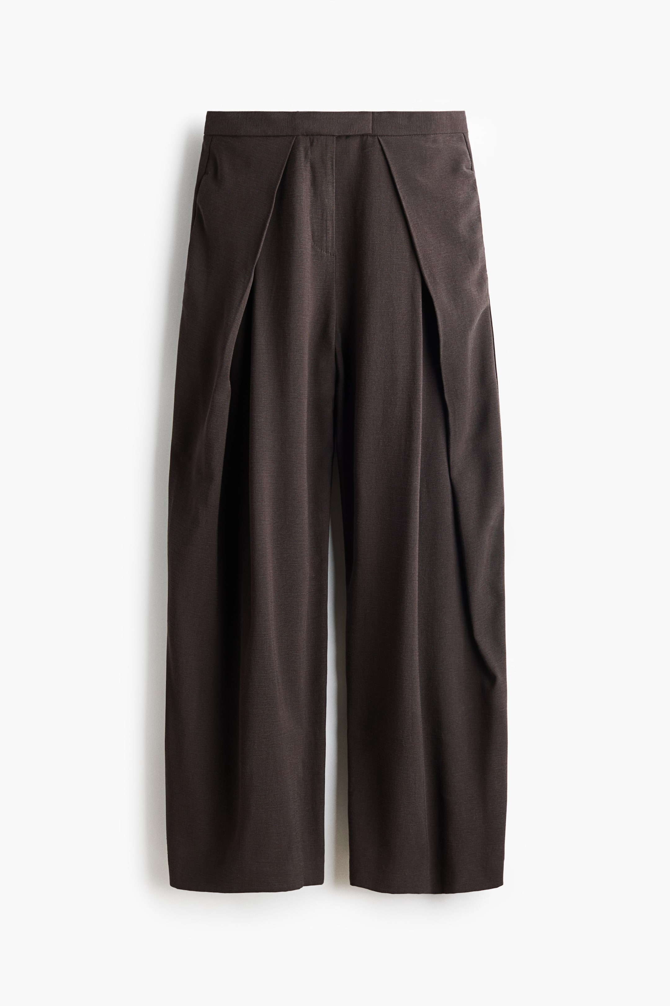 View larger image: Dark brown loose-fit trousers showcase a high waist with an extended waistband and a central zip fly. Discreet side pockets are visible, and the balloon legs feature wrapover sides.