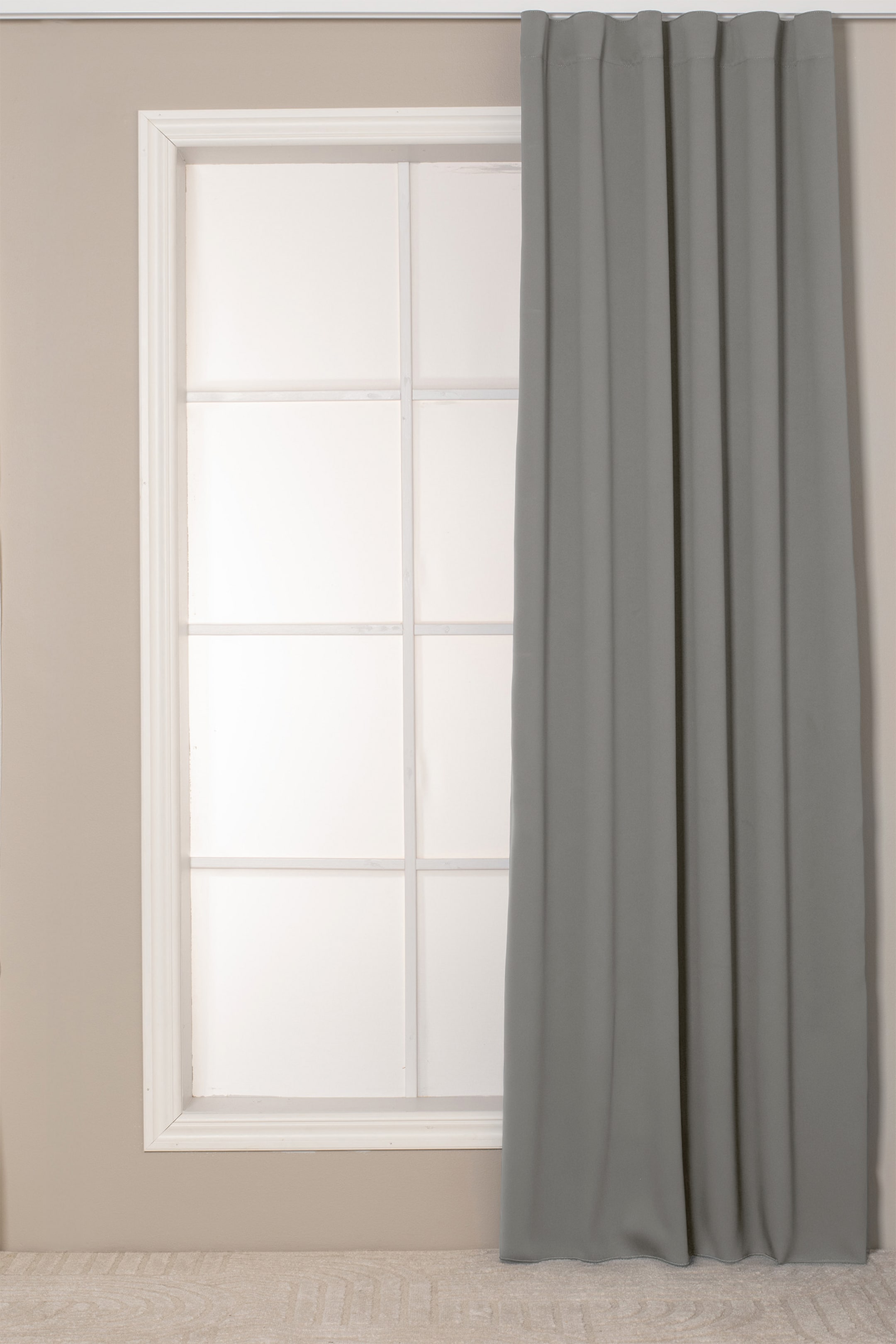 Grotere afbeelding bekijken: Een grijze gordijnpaneel hangt verticaal, met een geplooide bovenkant en valt in zachte, volle lengte verticale plooien. Het is volledig uitgestrekt gepresenteerd, van de bovenkant van het raamkozijn tot aan de vloer.