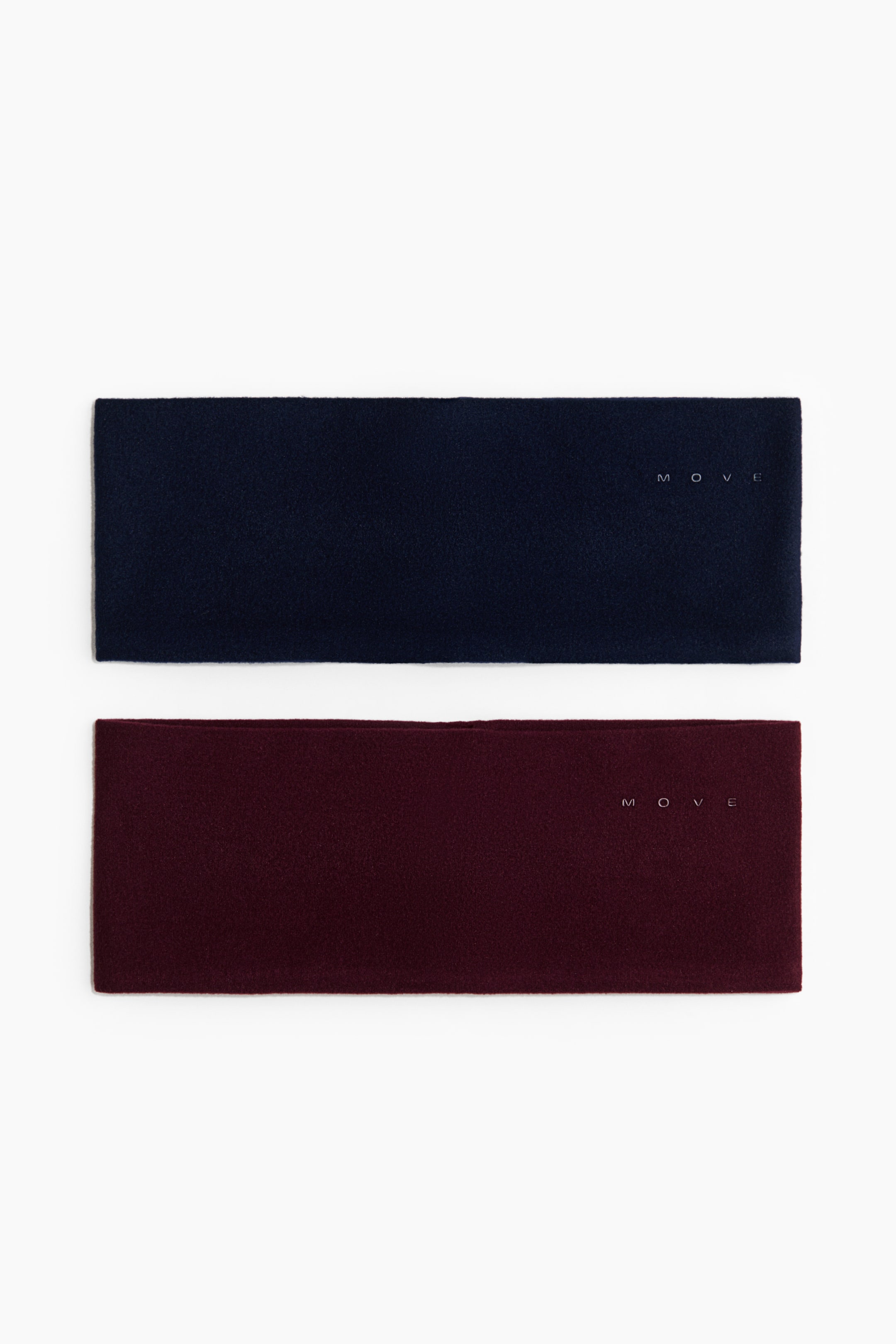 Ampliar la imagen: Dos bandas para la cabeza anchas de felpa, una en azul marino oscuro y otra en color borgoña, están colocadas planas y de frente. Ambas bandas muestran una textura suave y cepillada, así como un pequeño logotipo minimalista “MOVE” impreso en el lado derecho.