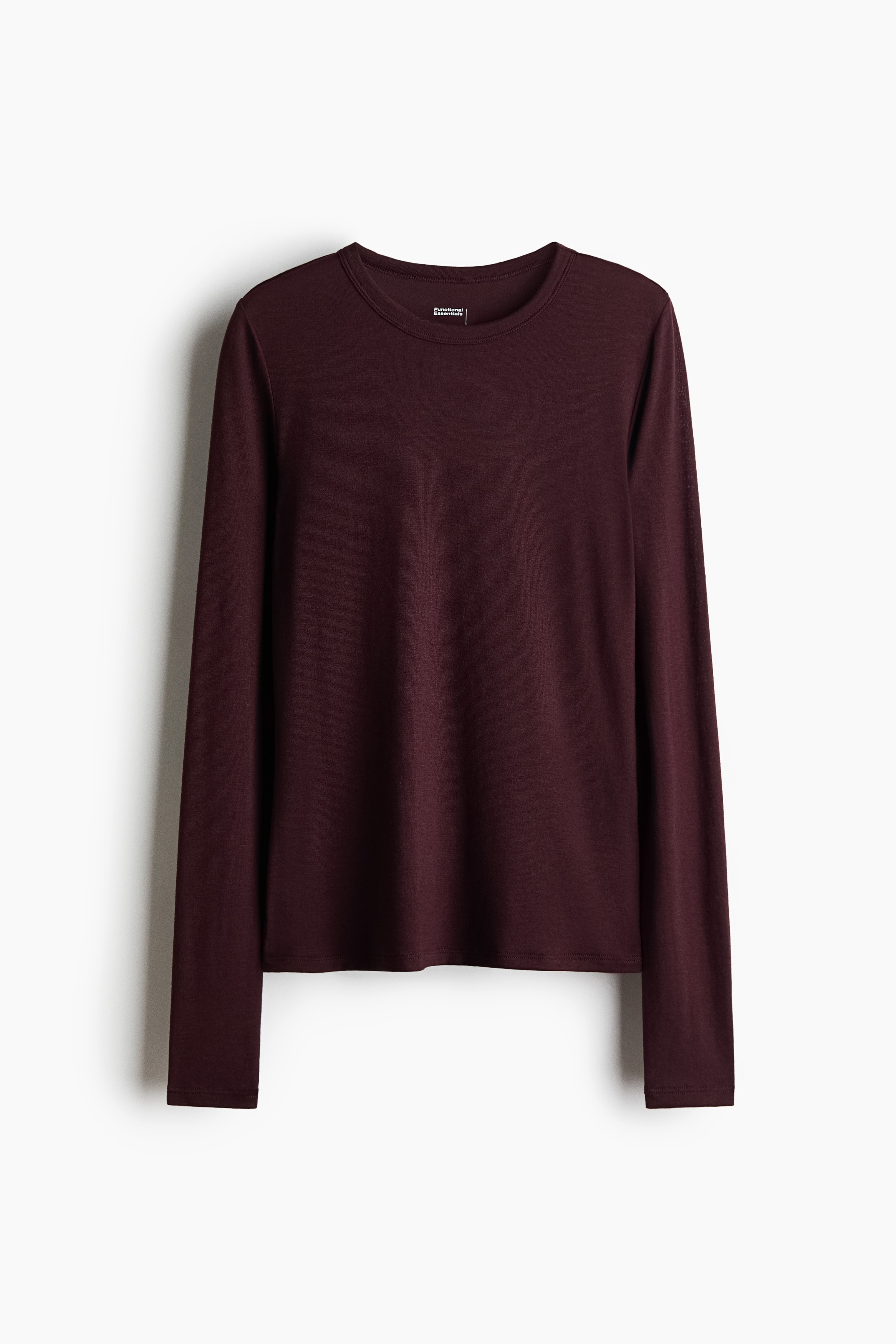 A dark plum, slim-fit long-sleeved top featuring a crew neck and a curved hem is being worn by the model. The top is layered over a light grey long-sleeved shirt, with the grey collar, cuffs and hem visible beneath it.