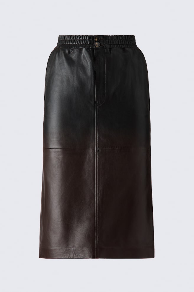 A calf-length leather skirt is shown front-facing, featuring a smocked elasticated waistband and a buttoned zip-fly fastening. The skirt features a two-tone panel design that transitions from black at the top to dark brown at the bottom, divided by a horizontal seam and defined by a vertical centre seam. - 1