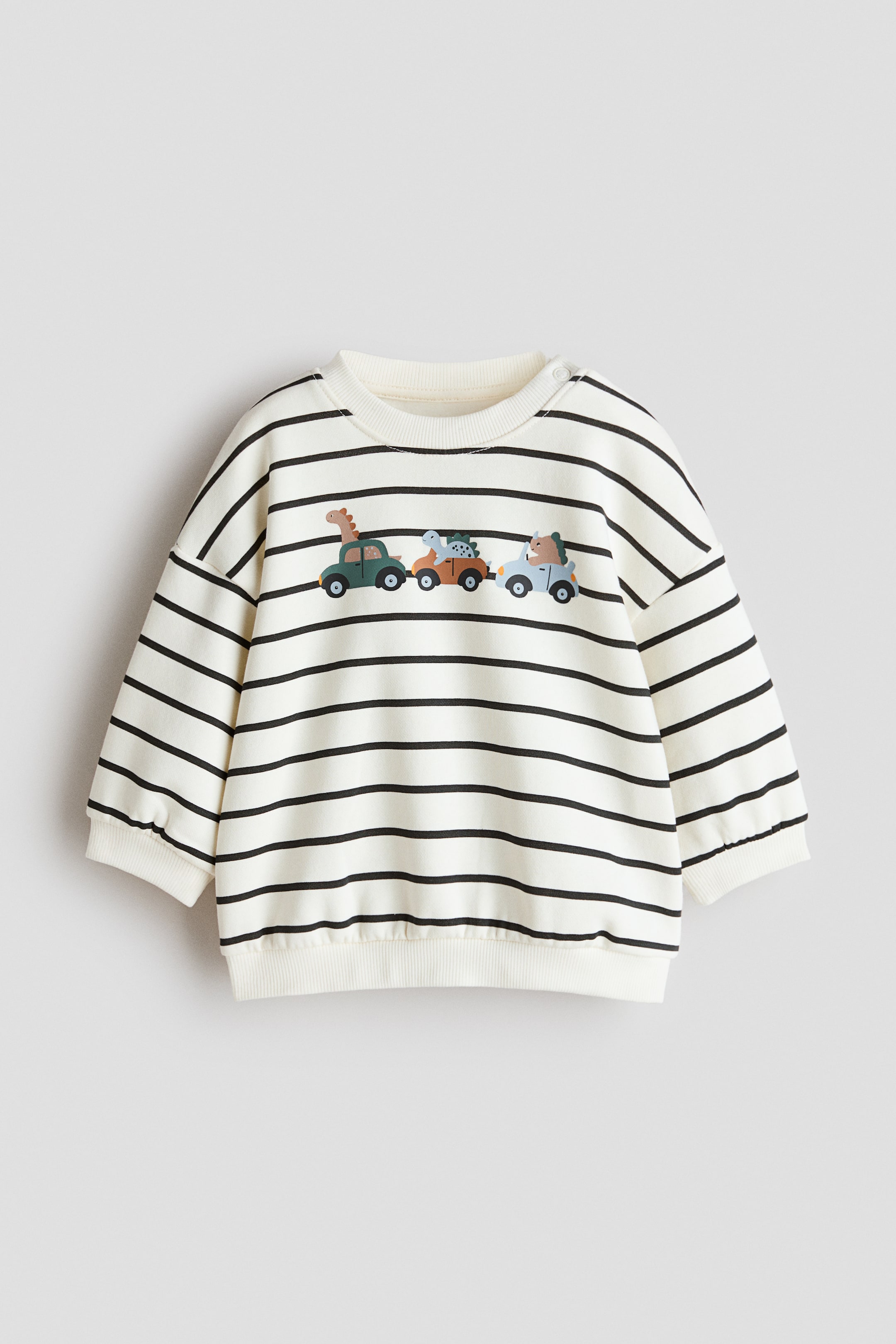 View larger image: Printed sweatshirt. This cream sweatshirt showcases horizontal black stripes and a graphic print featuring three cartoon vehicles, each carrying an animal, across the chest. It comes with a ribbed crew neck, two snap buttons on the left shoulder, long sleeves with ribbed cuffs, and a ribbed hem, all facing forward.