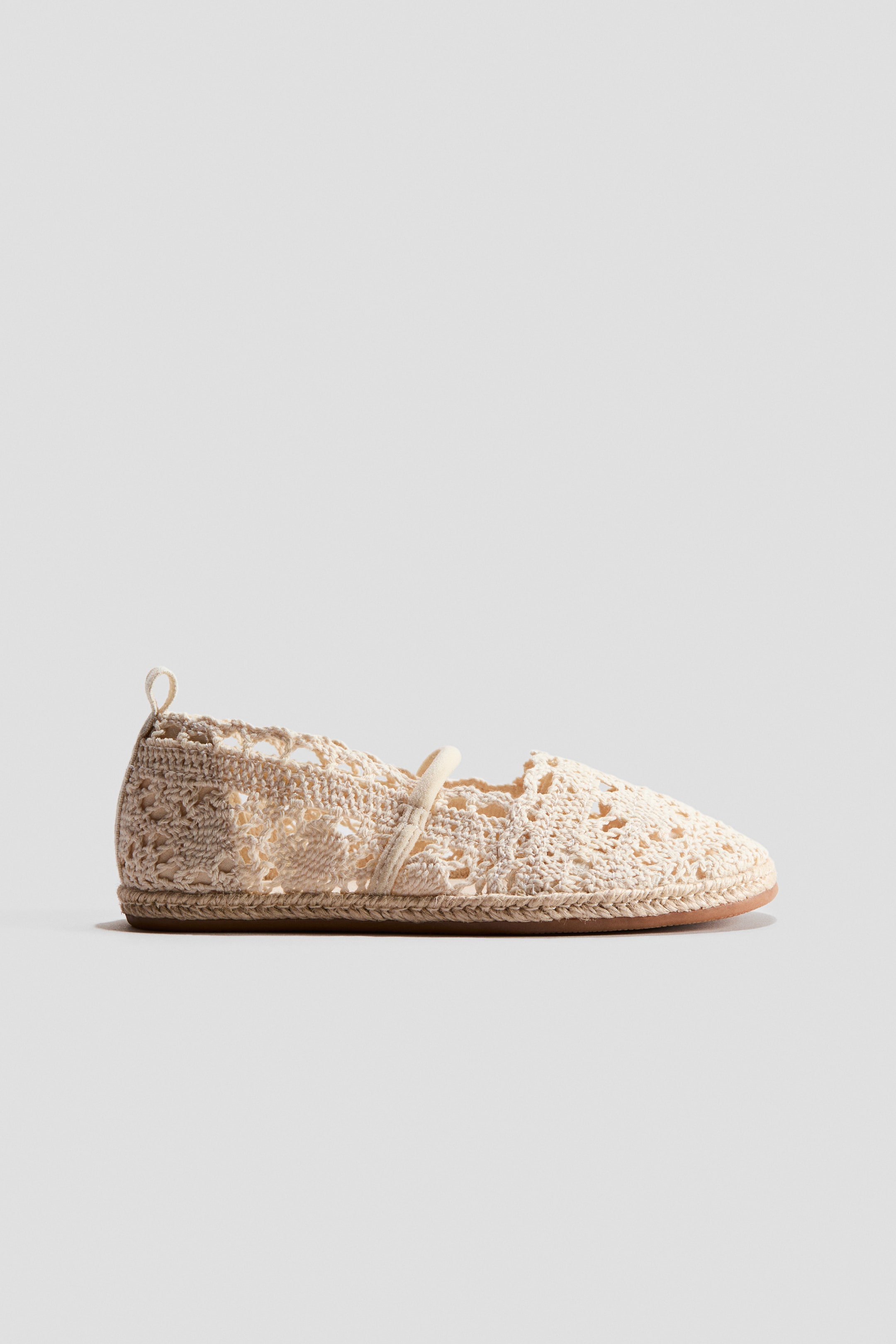 View larger image: The espadrille features a light beige crocheted upper with an open-knit design, rounded toes, and a slim strap across the foot. A small loop is positioned at the back, and the soles are encircled with braided jute trim.