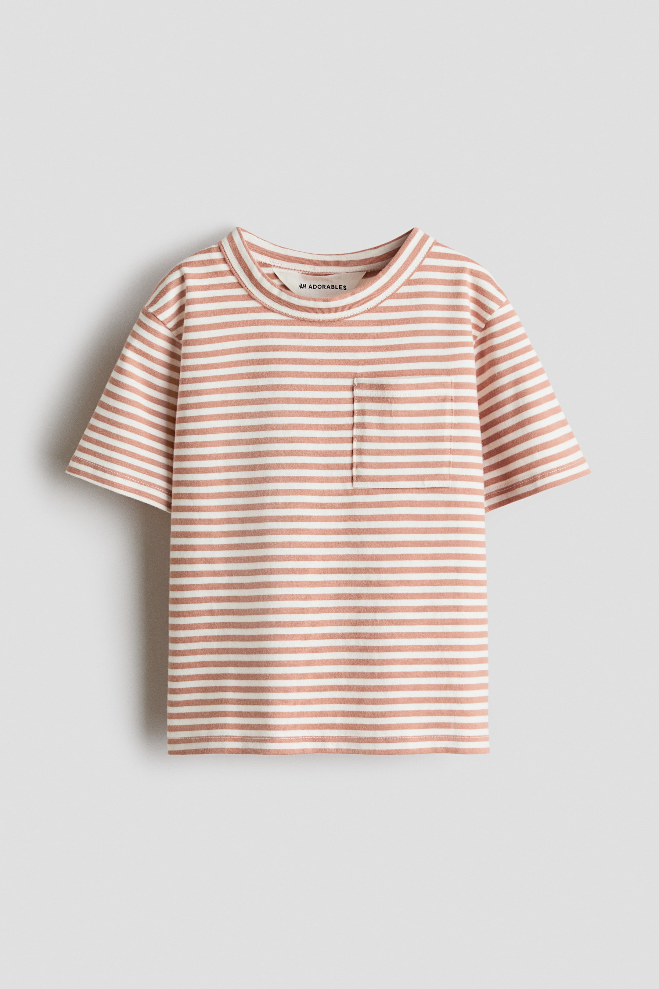 Größeres Bild anzeigen: Ein nach vorne gerichtetes T-Shirt zeigt off-white und gedämpft rötlich-braune horizontale Streifen. Es verfügt über einen runden, eingefassten Halsausschnitt, überschnittene Schultern, kurze Ärmel und eine aufgesetzte Brusttasche auf der linken Seite.