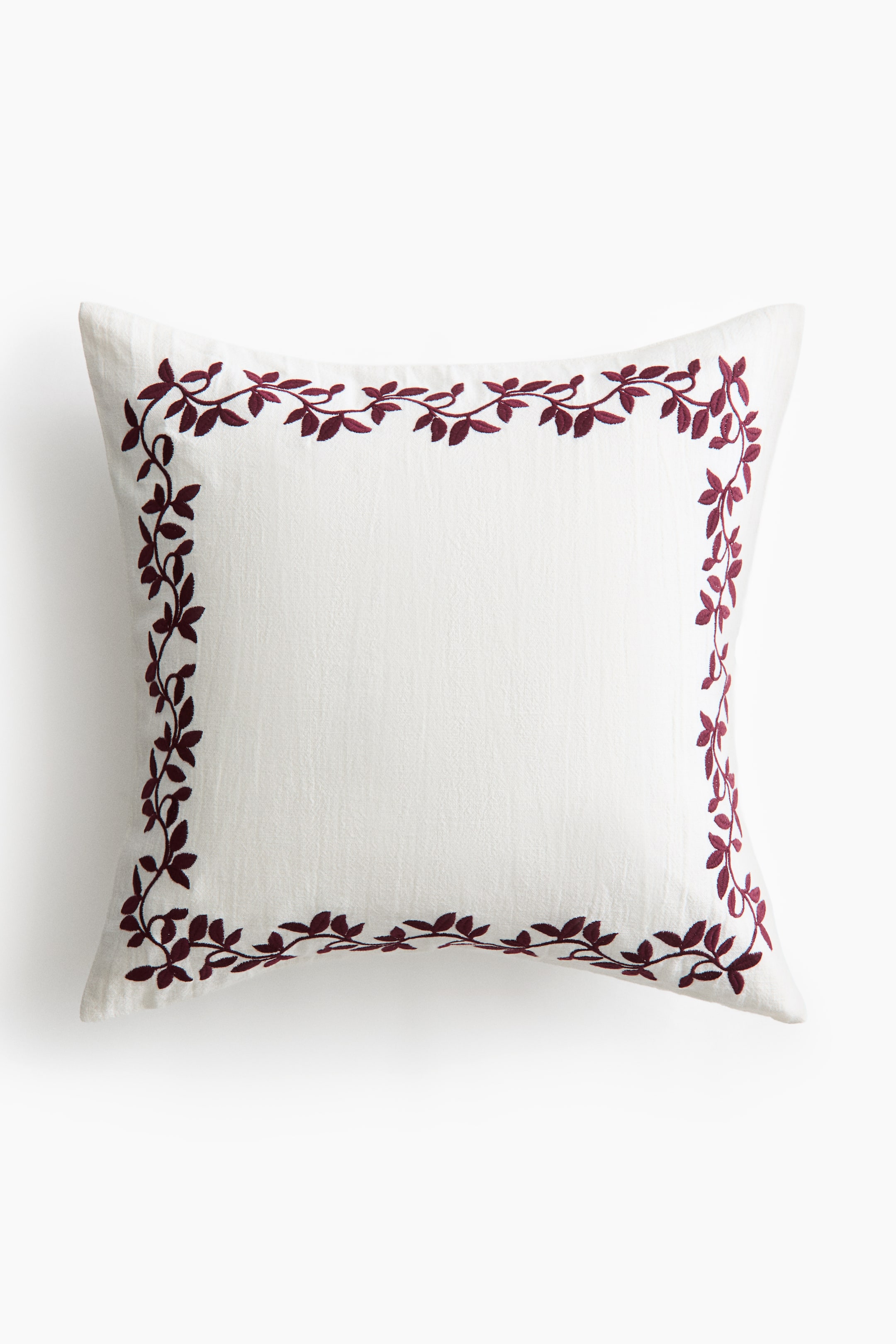 View larger image: A square off-white cushion is facing front, featuring a dark burgundy embroidered vine-and-leaf border framing the outer edges of its textured slub fabric.